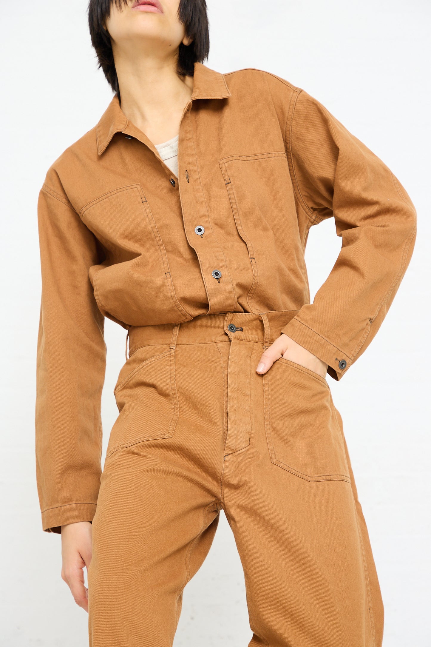 Woman in a Chimala Classic Drill US Army Work Trouser in Camel jumpsuit with hands on her hips against a white background.