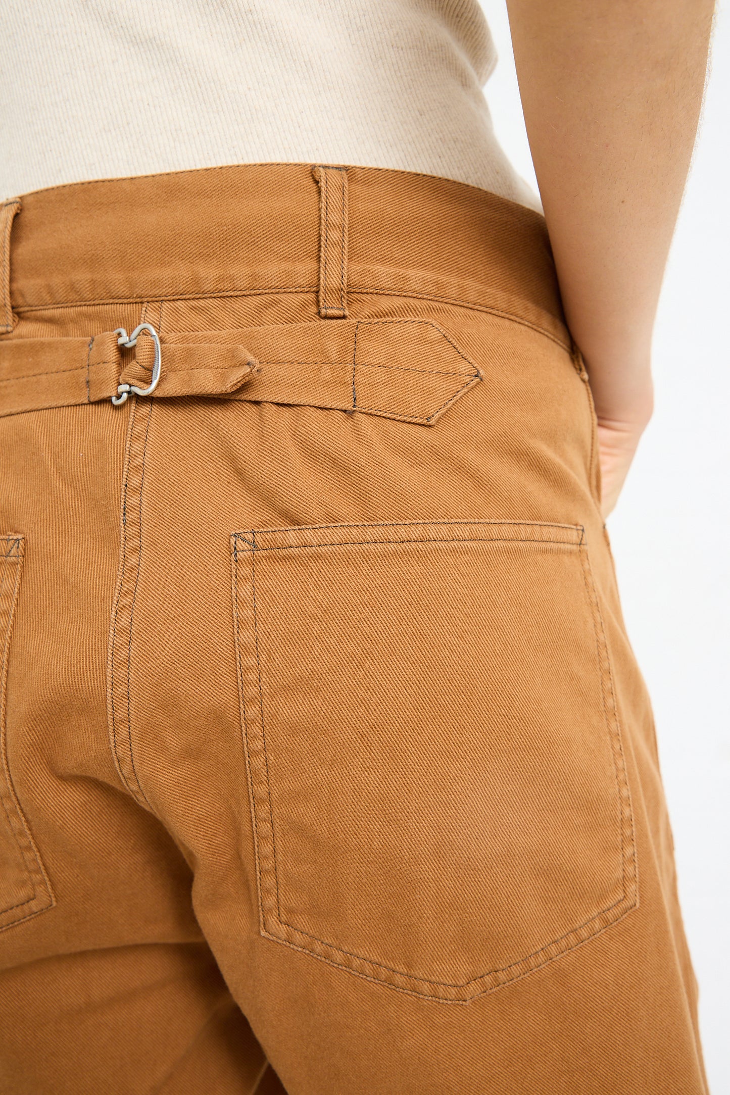 Close-up of the back of a person wearing Chimala Classic Drill US Army Work Trouser in Camel with a belt loop tie detail, crafted from Japanese cotton canvas.
