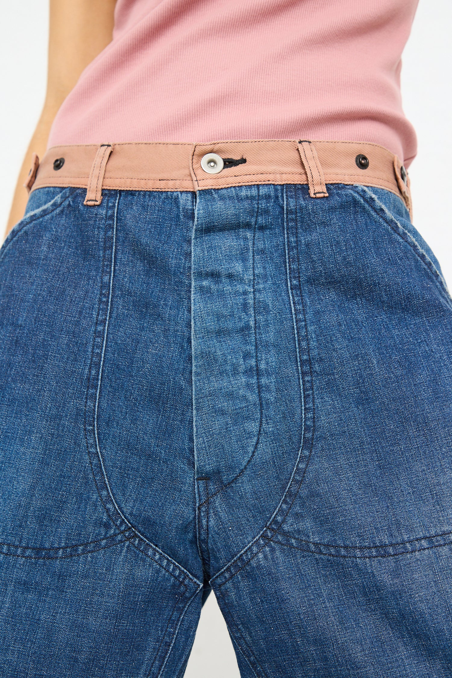 Close-up of a woman wearing Denim Double Knee Work Pant in Indigo crafted by Japanese denim artisans with a pink top and tan belt by Chimala.