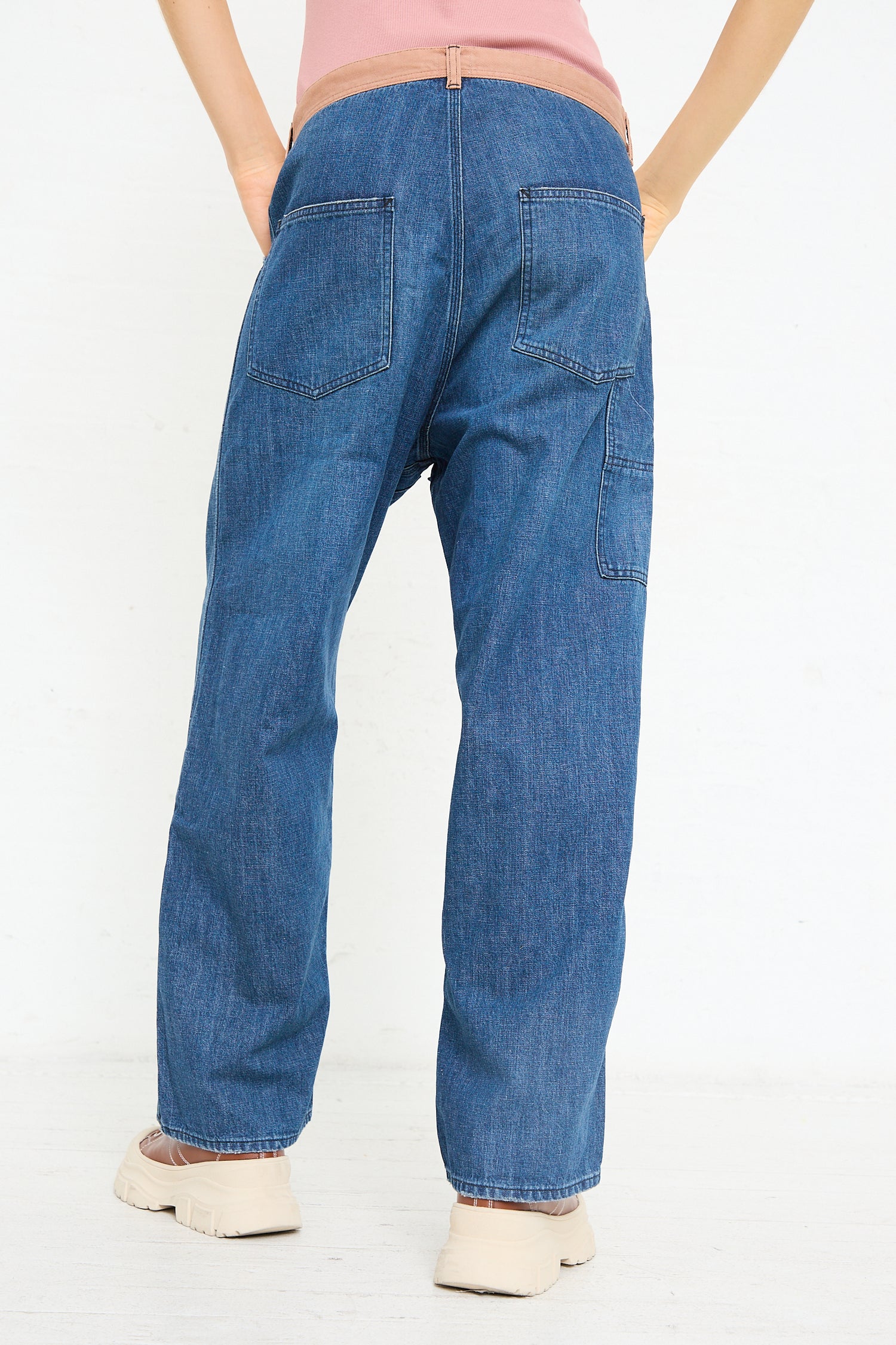 A person from behind wearing blue Chimala selvedge denim carpenter pants and white shoes.