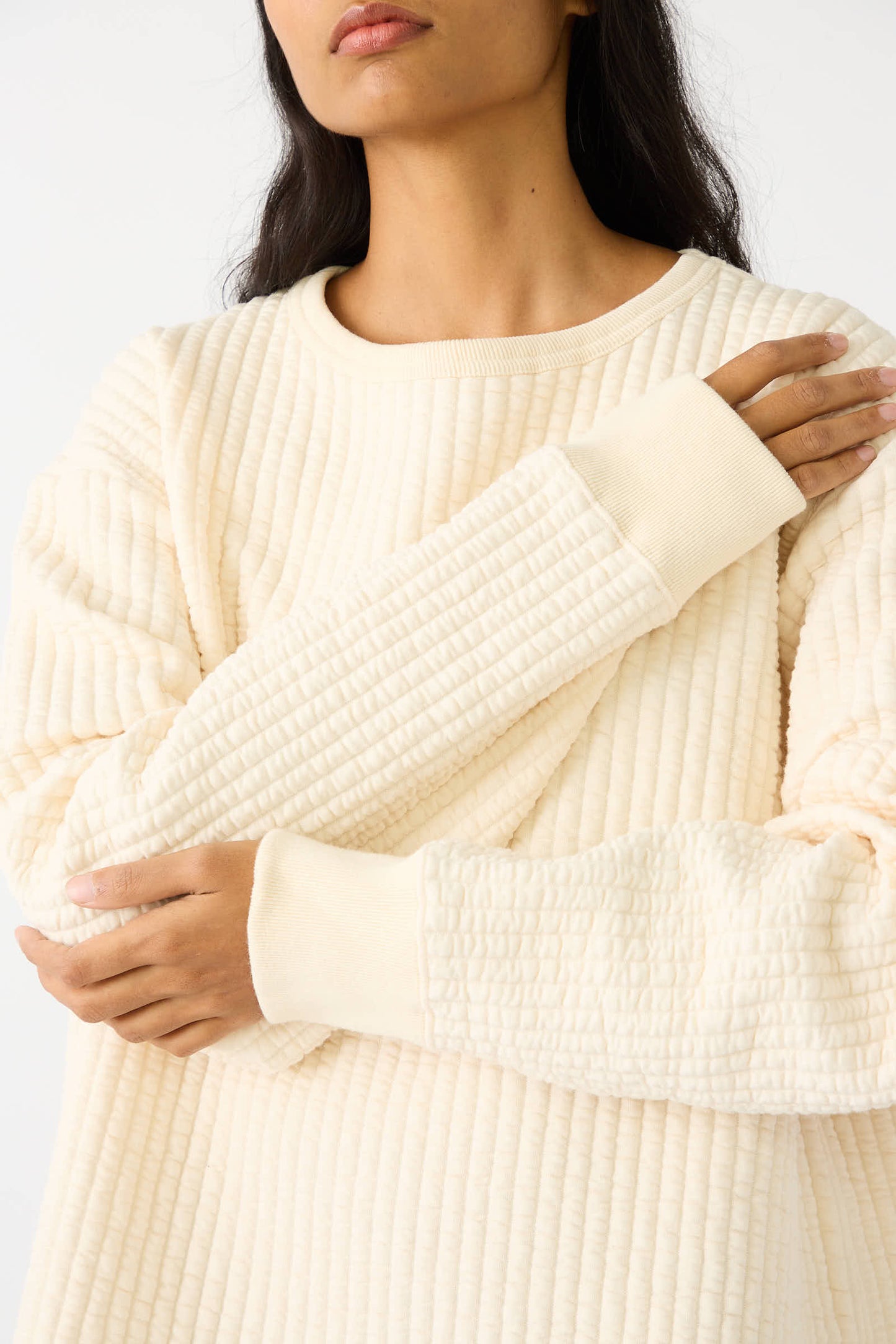 Person wearing a Chimala Quilted Crew Neck Top in Ivory with hands folded over the chest.