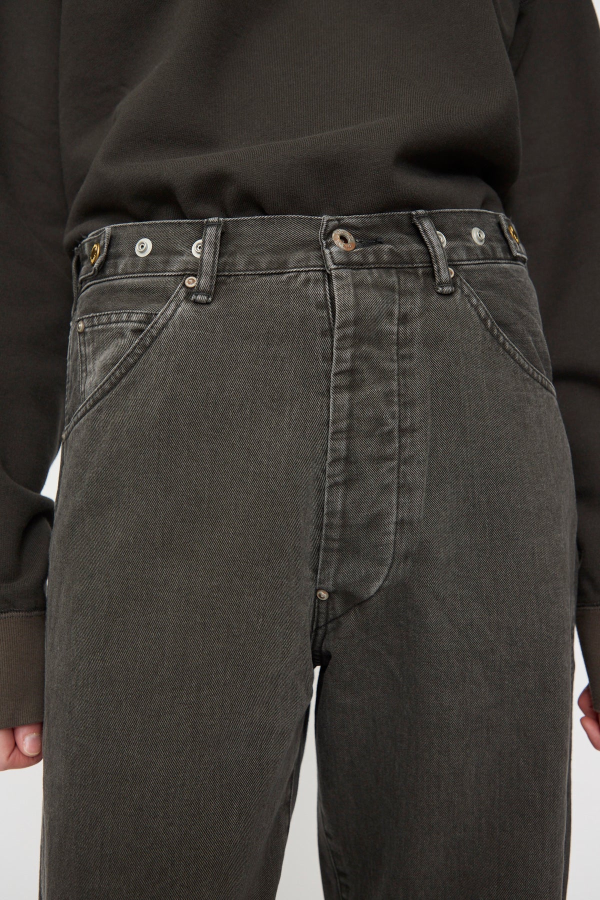 Wearing Chimala’s Rope Dyed Twill Adjustable Pant in Charcoal—a high-waisted Japanese-made denim featuring visible belt loops, buttons, and front pockets—styled with a dark long-sleeve shirt.