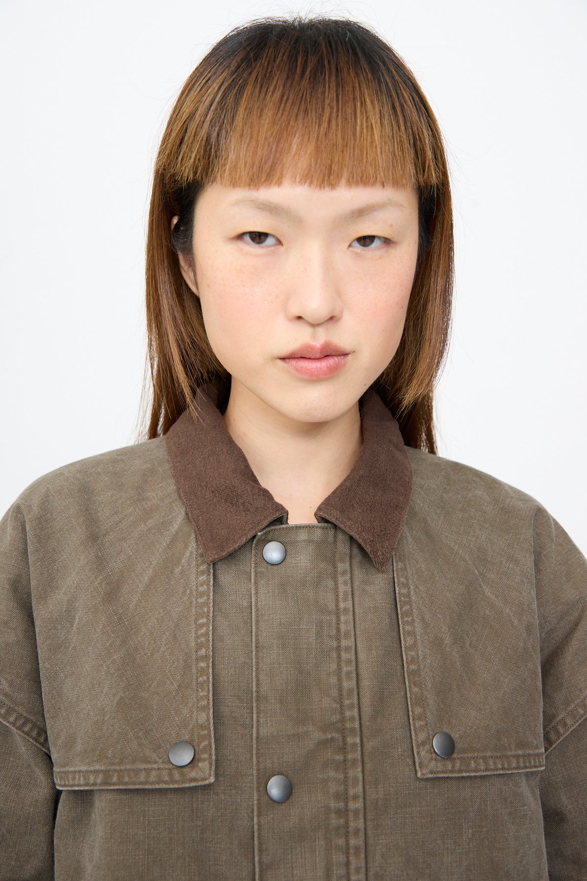 A Chimala Sulfer Dyed Canvas Lumber Coat in brown, featuring an oversized fit, contrasting collar, and snap buttons.