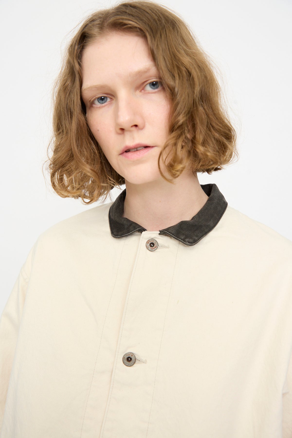 A person with short, wavy light brown hair is wearing the Chimala Twill Engineer Jacket in Ivory Splatter, looking at the camera against a plain light background.