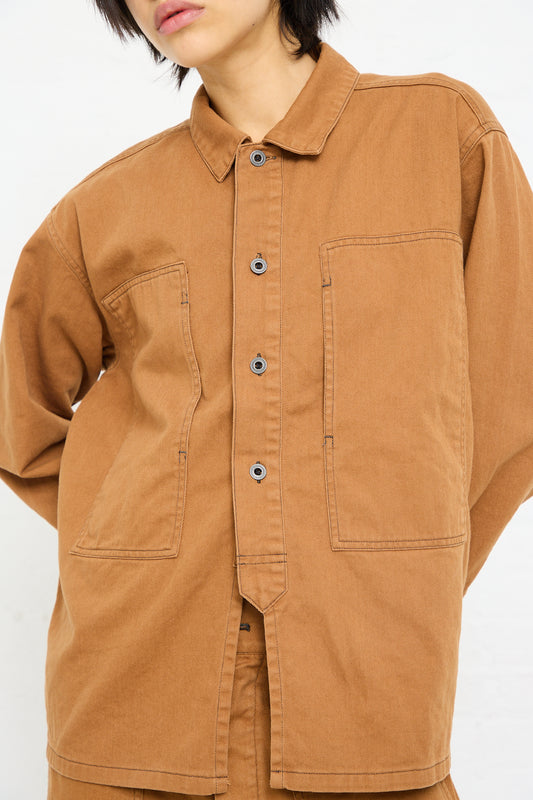 Person wearing a Chimala Unisex Classic Drill US Army Work Jacket in Camel with large pockets.
