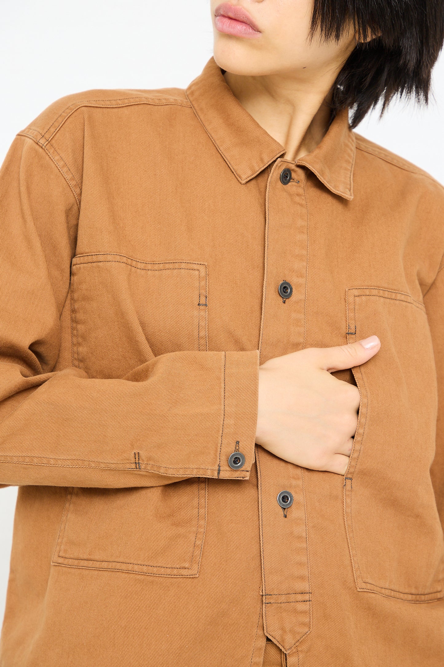A person wearing a Chimala Unisex Classic Drill US Army Work Jacket in Camel with their hand on their hip.
