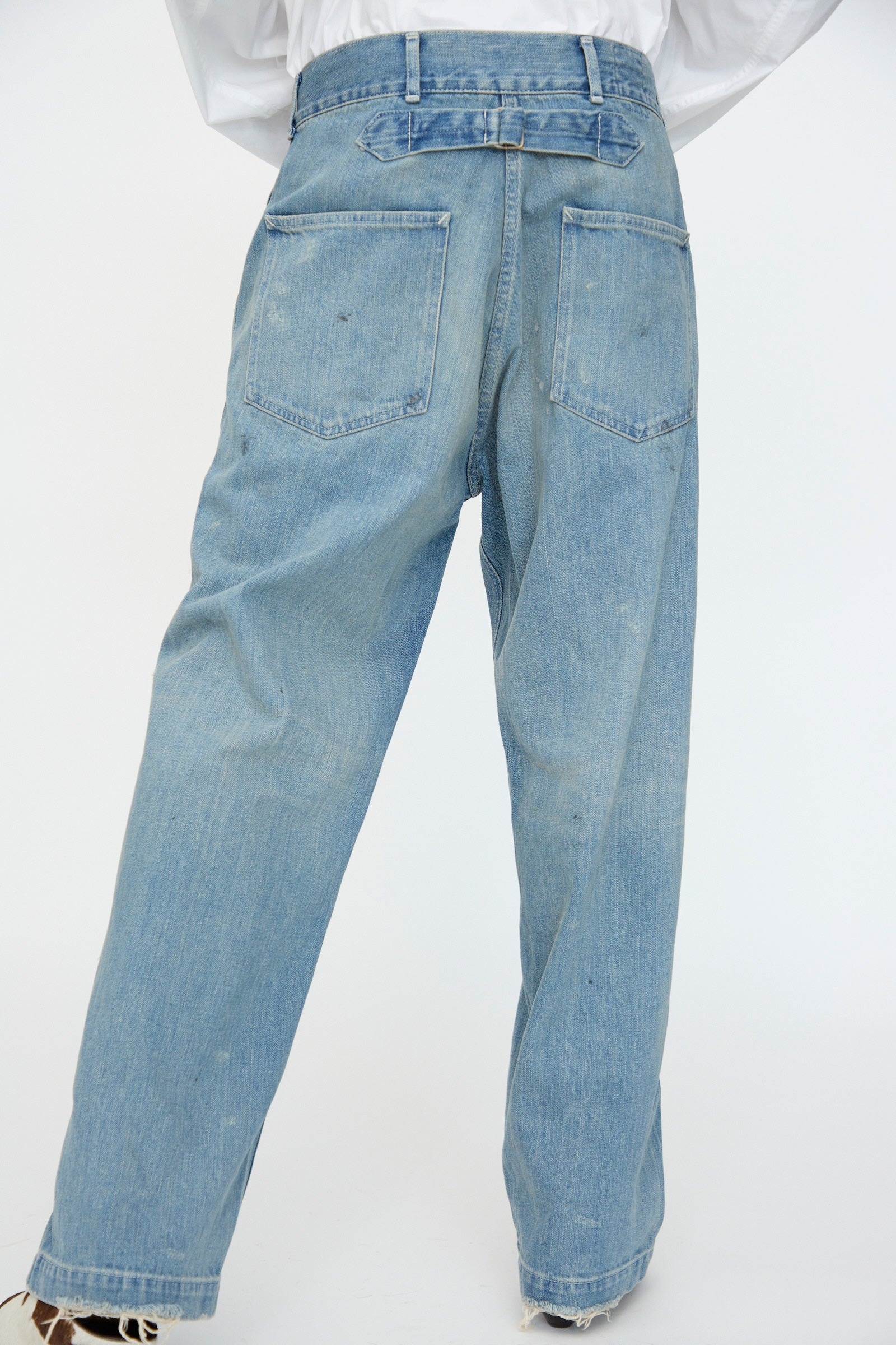 Model wearing Chimala's Unisex US Army Style Denim Trouser in Light Vintage, featuring a high waist and relaxed fit with two large back pockets, photographed from the back against a plain white background.