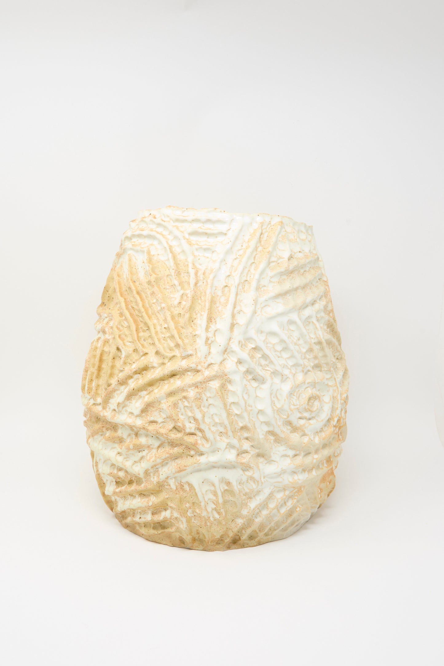 A textured, hand-built ceramic vase—the Large Ridge Vase in Yellow by Claire Resnick Ceramics—features raised swirling and leaf-like patterns across its tan and white surface, shown against a plain white background.