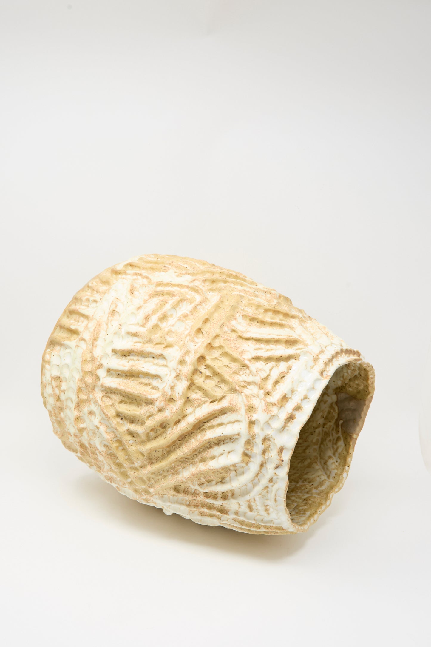 A large, textured yellow ceramic vase by Claire Resnick Ceramics, named the Large Ridge Vase, lies on its side against a plain white background.