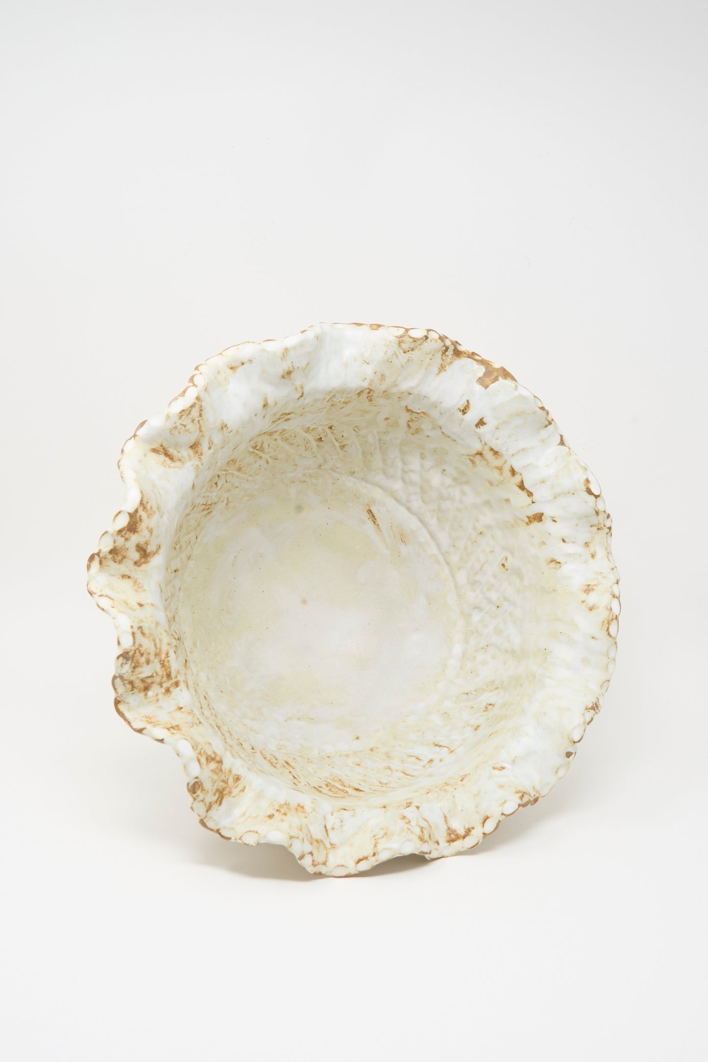 The Large Ridge Wave Bowl by Claire Resnick Ceramics is an irregularly shaped, hand-built ceramic piece featuring a textured off-white surface and brownish edges, crafted in the USA and photographed against a plain white background.
