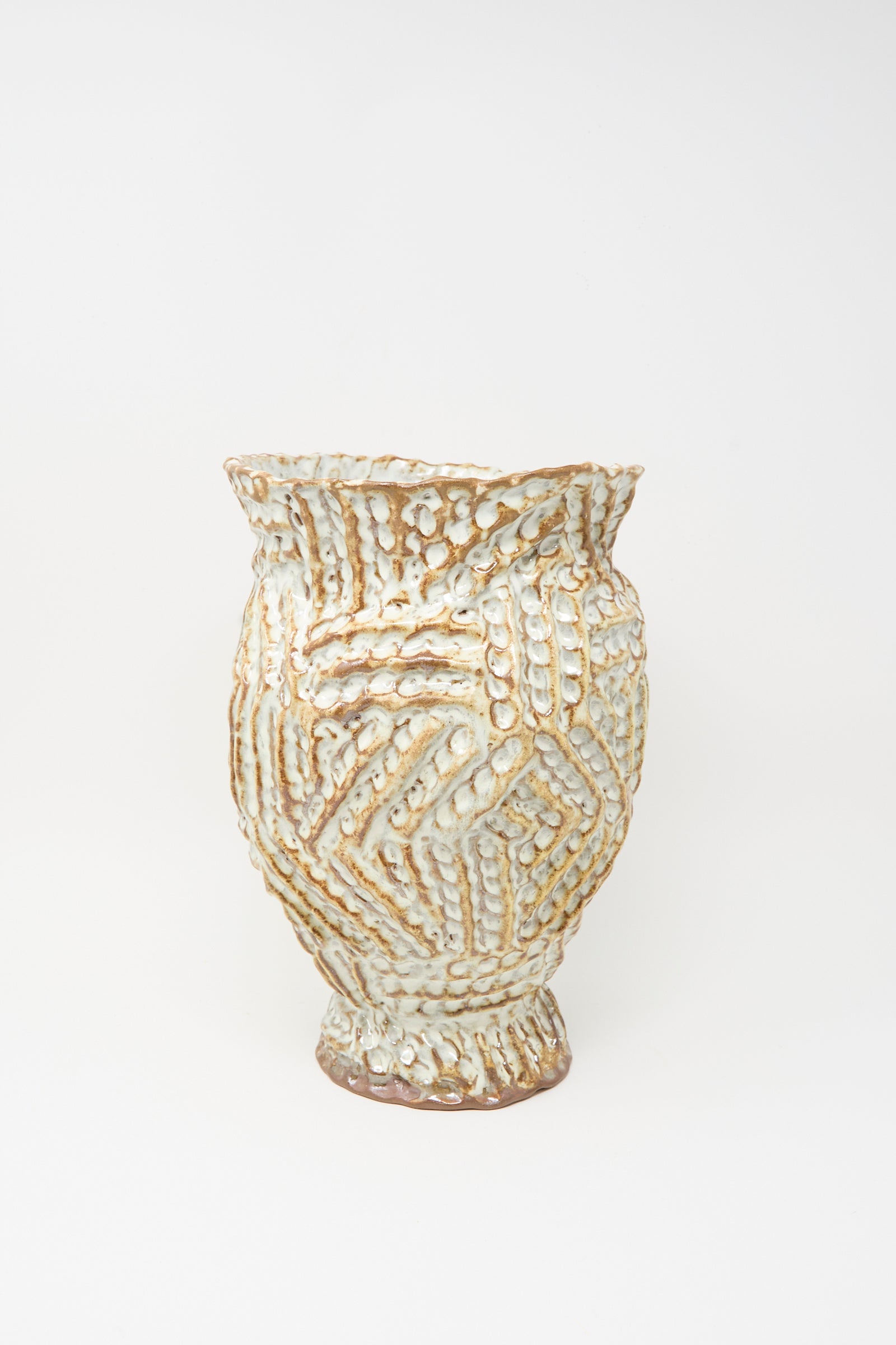 The Ridge Vase in Brown by Claire Resnick Ceramics is a hand-built ceramic piece with raised zigzag patterns and an uneven rim, finished in a cream and brown glaze, displayed against a plain white background.