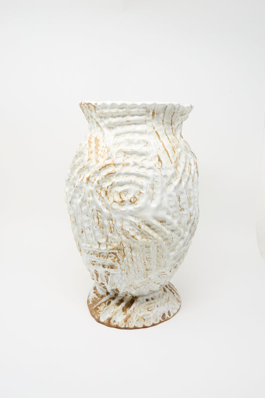 The Ridge Vase in White by Claire Resnick Ceramics displays a wavy, ridged surface pattern with a white and beige glaze. Set against a plain white background, this handmade ceramic vase embodies both elegance and artistry in its distinctive form.