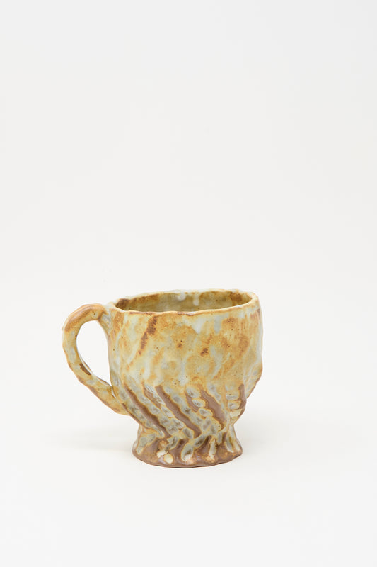 The Textured Mug in Rust Mix I by Claire Resnick Ceramics features an uneven, hand-built ceramic surface in earthy tones of brown, yellow, and beige, displayed against a plain white background.