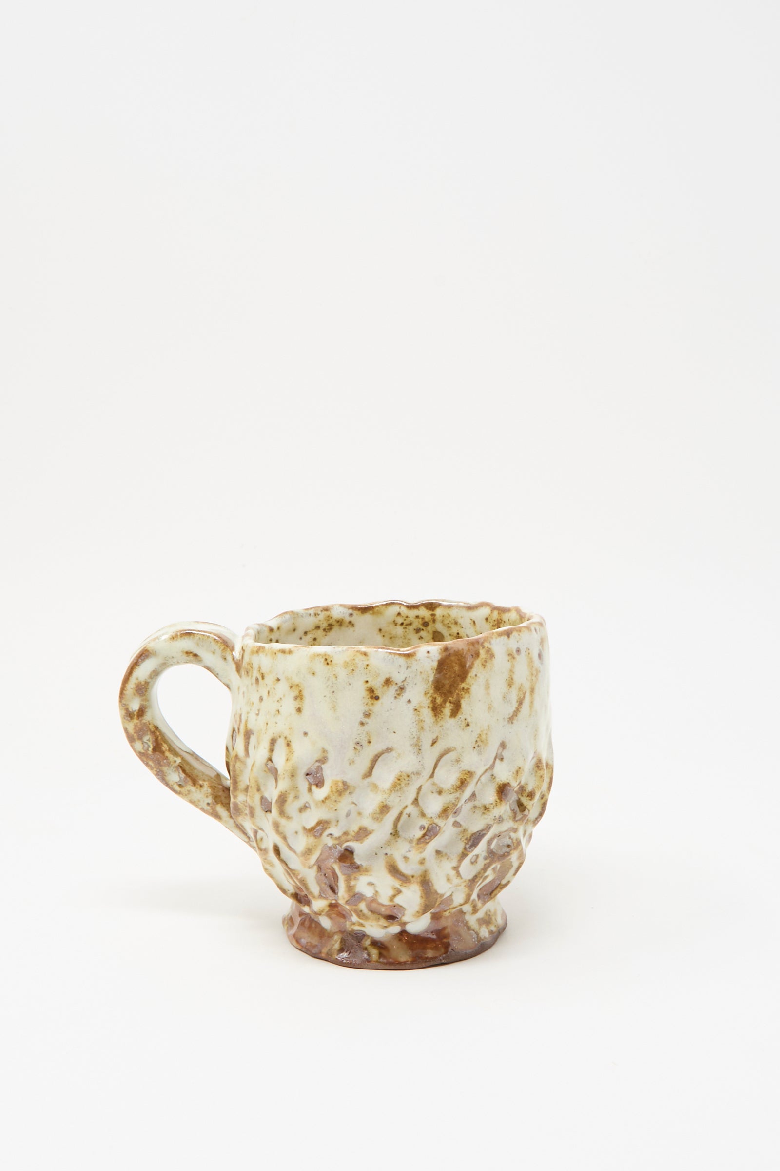 The Claire Resnick Ceramics Textured Mug in White Brown Mix I is displayed against a plain white background, featuring a handmade, dimpled ceramic surface with a blend of cream and brown glaze. Crafted in the USA, this unique hand-built mug highlights exceptional craftsmanship and distinctive style.