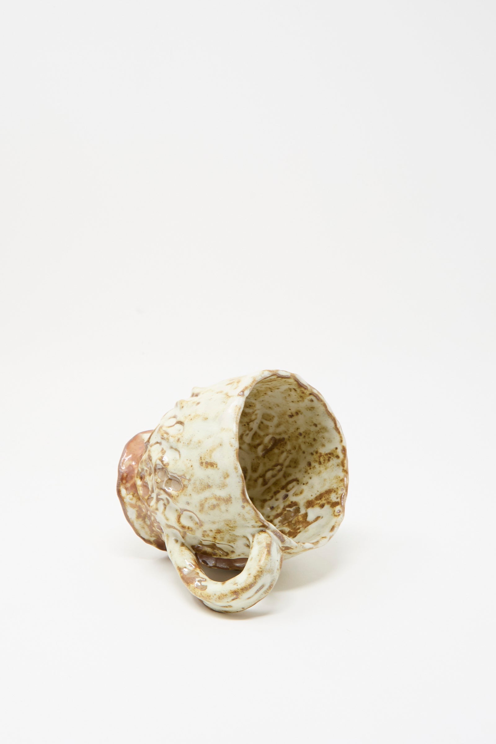 The Textured Mug in White Brown Mix I from Claire Resnick Ceramics rests on its side against a plain white background, highlighting its handcrafted quality, unique beige and brown glaze, and expert craftsmanship made in the USA.