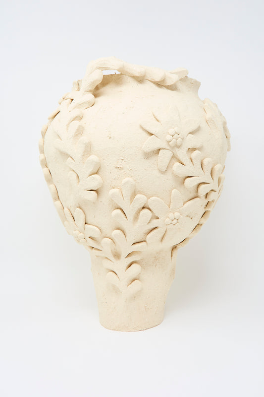 The Le Jardin Enchanté Tall Amphora Vase by Clandestine features a beige ceramic finish, wide body, narrow base, and raised floral and leaf patterns, crafted from natural clay and shown against a plain white background.