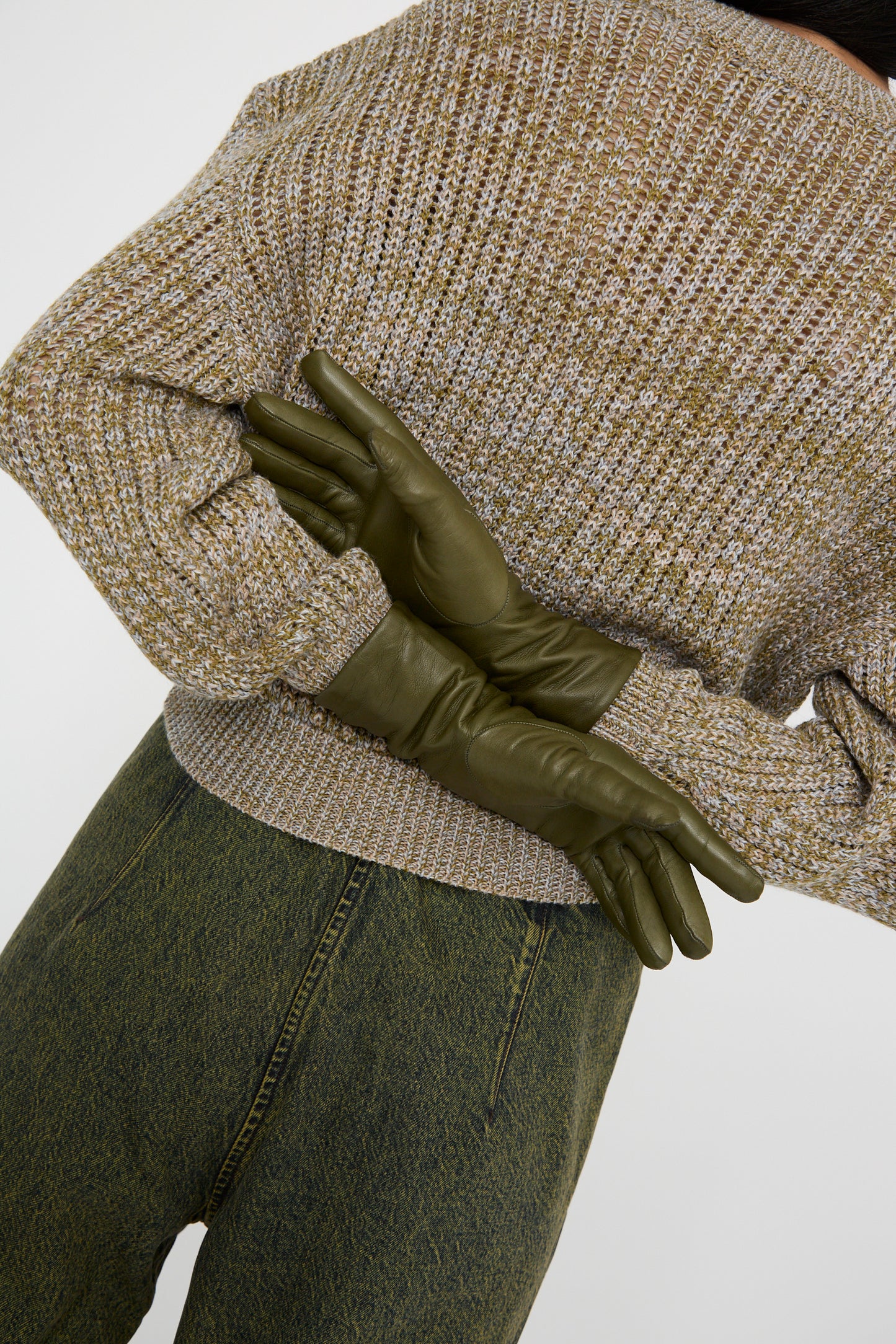 A person from the back dressed in a brown sweater and dark green pants, wearing the Clyde Lambskin and Cashmere Classic Glove in Bog Green.