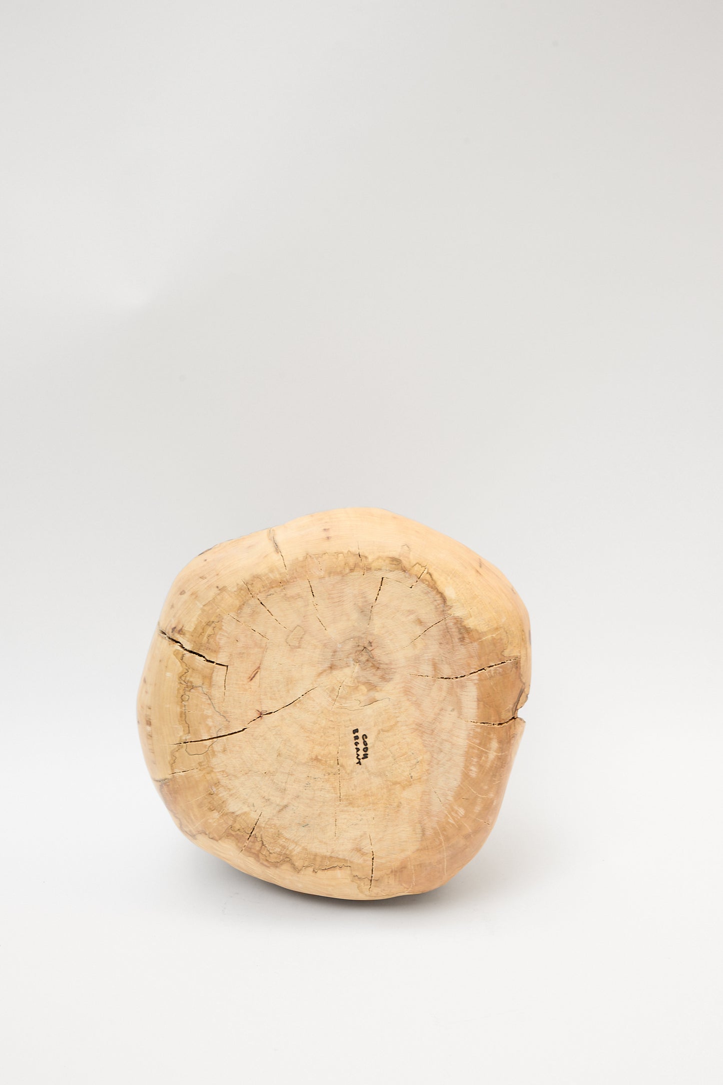 A small, round log of natural maple tree with visible cracks and a light wood grain, standing on a white surface with a plain background. The Fort Greene Maple Pouf by Cody Brgant is handmade in Brooklyn.