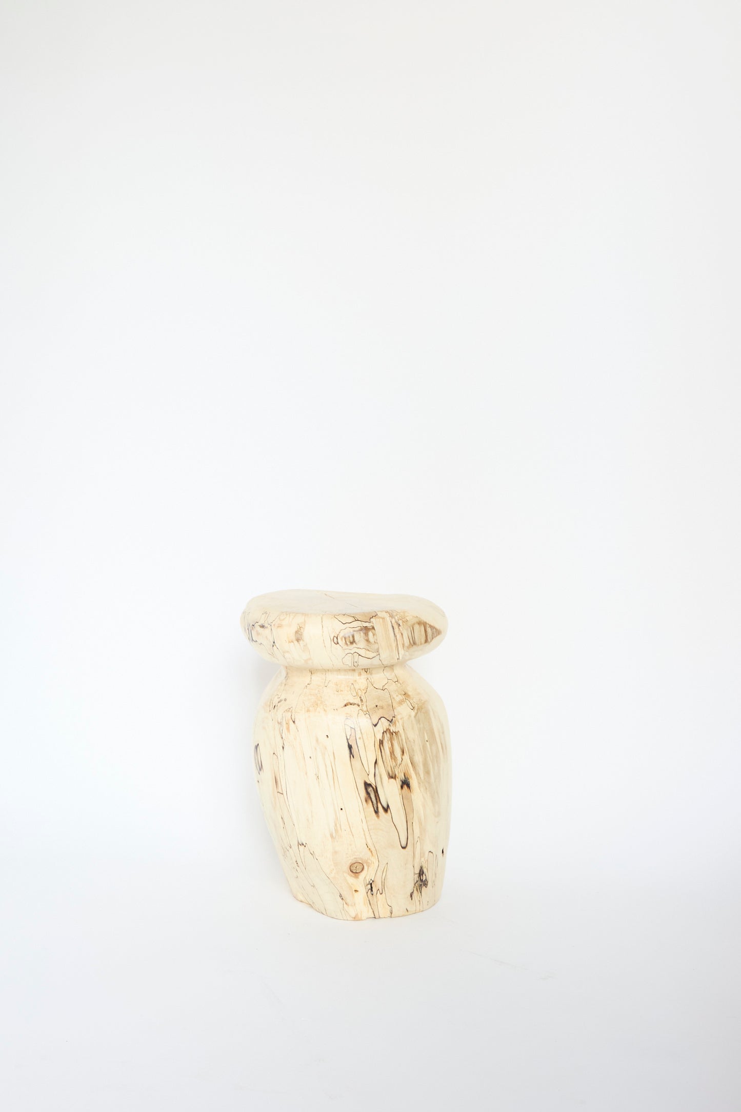 A wooden stool with a smooth, rounded seat and light wood grain stands against a plain white background, the Kingston Spalted Maple Vase by Cody Brgant.