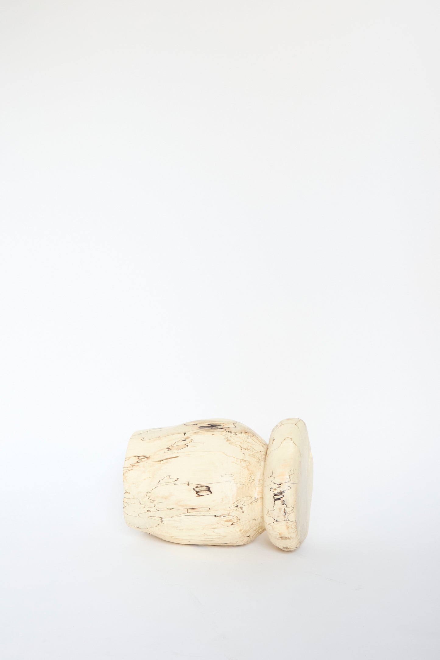 A light beige wood sculpture resembling the Kingston Spalted Maple Vase by Cody Brgant, lies on its side against a plain white background.