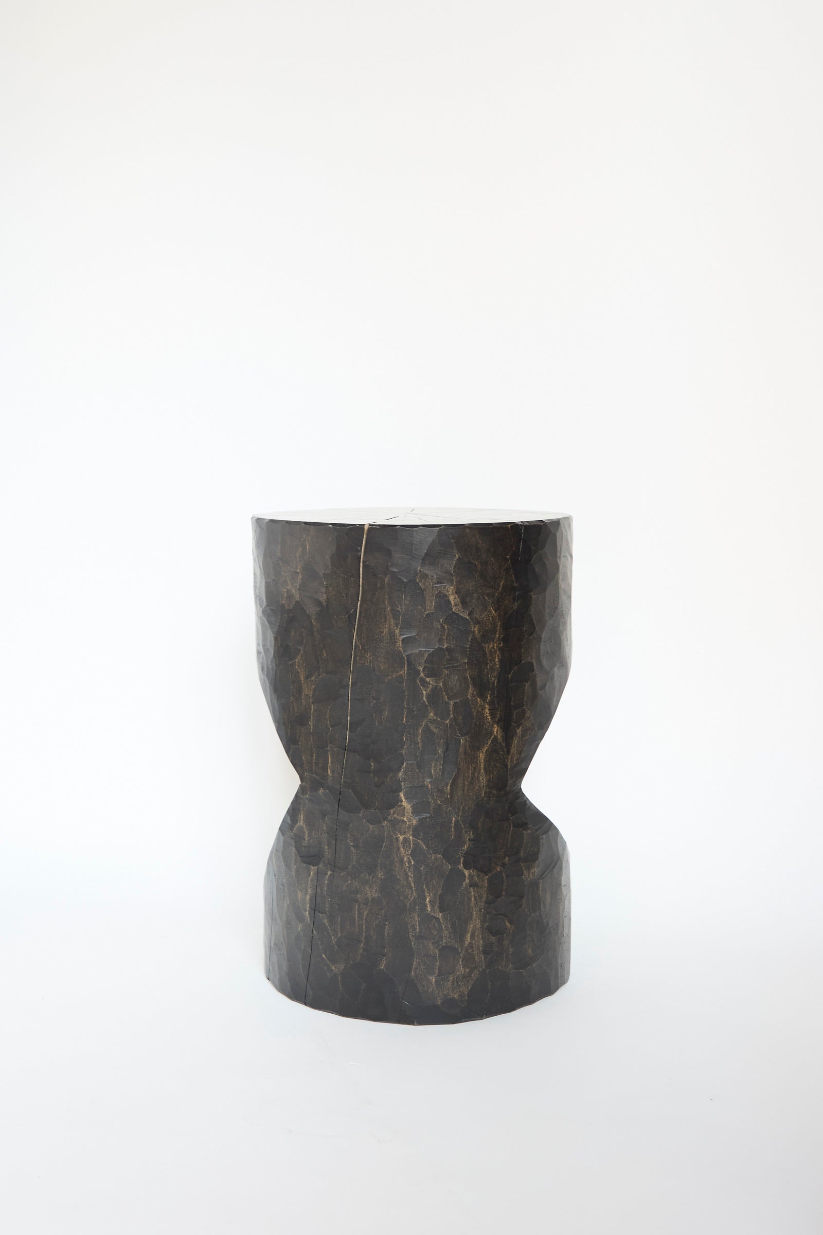 The Windsor Terrace Sycamore Side Table with Oak Inlay by Cody Brgant, featuring a textured dark brown cylindrical design with a tapered middle, stands elegantly against a plain white background, facing away. 