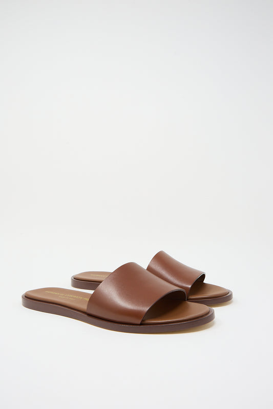 A pair of luxury Common Projects Leather Slide 6155 sandals in Brown Nappa leather against a white background.