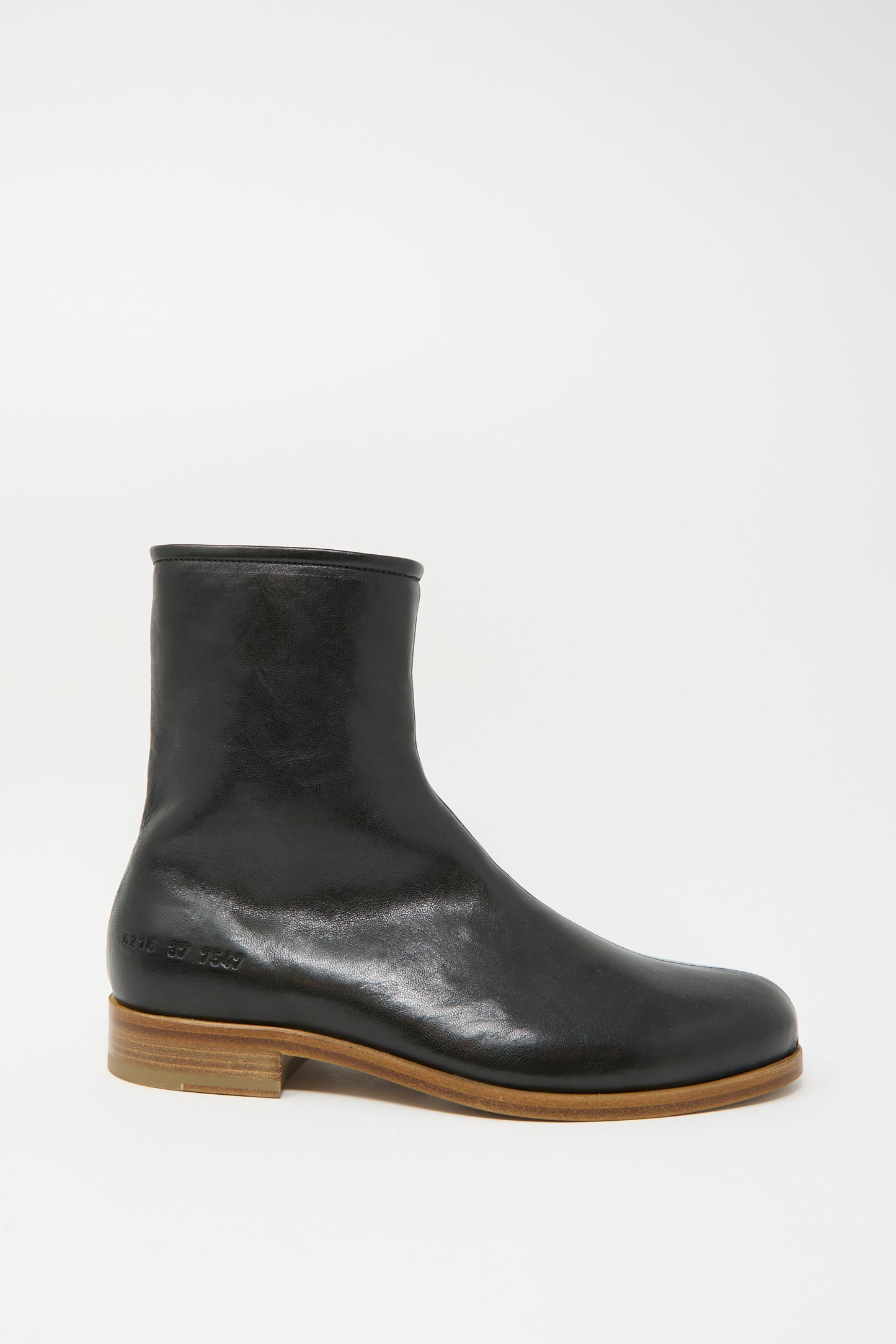 The Common Projects Zipper Boot Article 6216 in Black is a black leather ankle boot with a rounded toe and wooden sole, made in Italy, displayed in a side view against a white background.