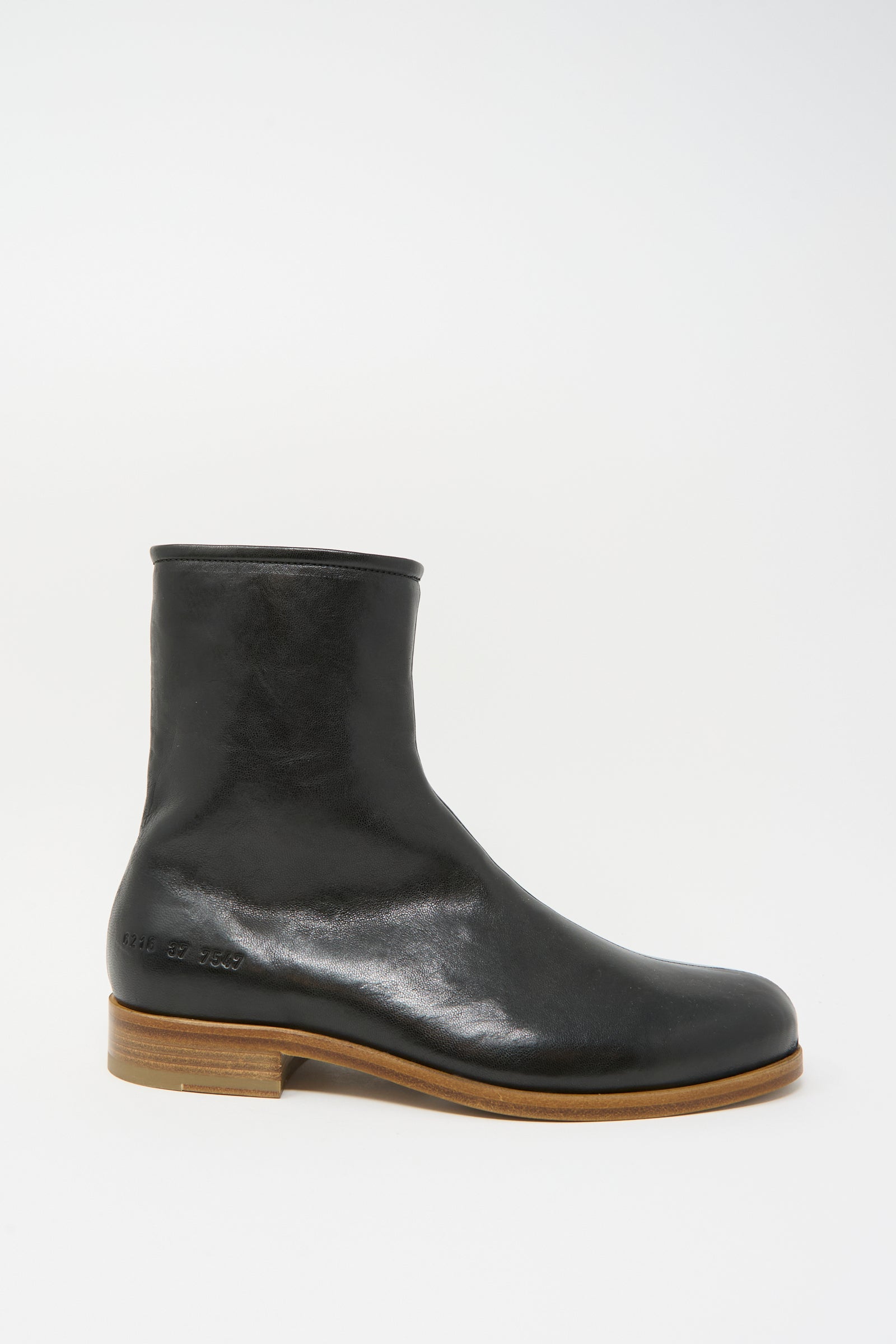 The Common Projects Zipper Boot Article 6216 in Black is a black leather ankle boot with a rounded toe and wooden sole, made in Italy, displayed in a side view against a white background.