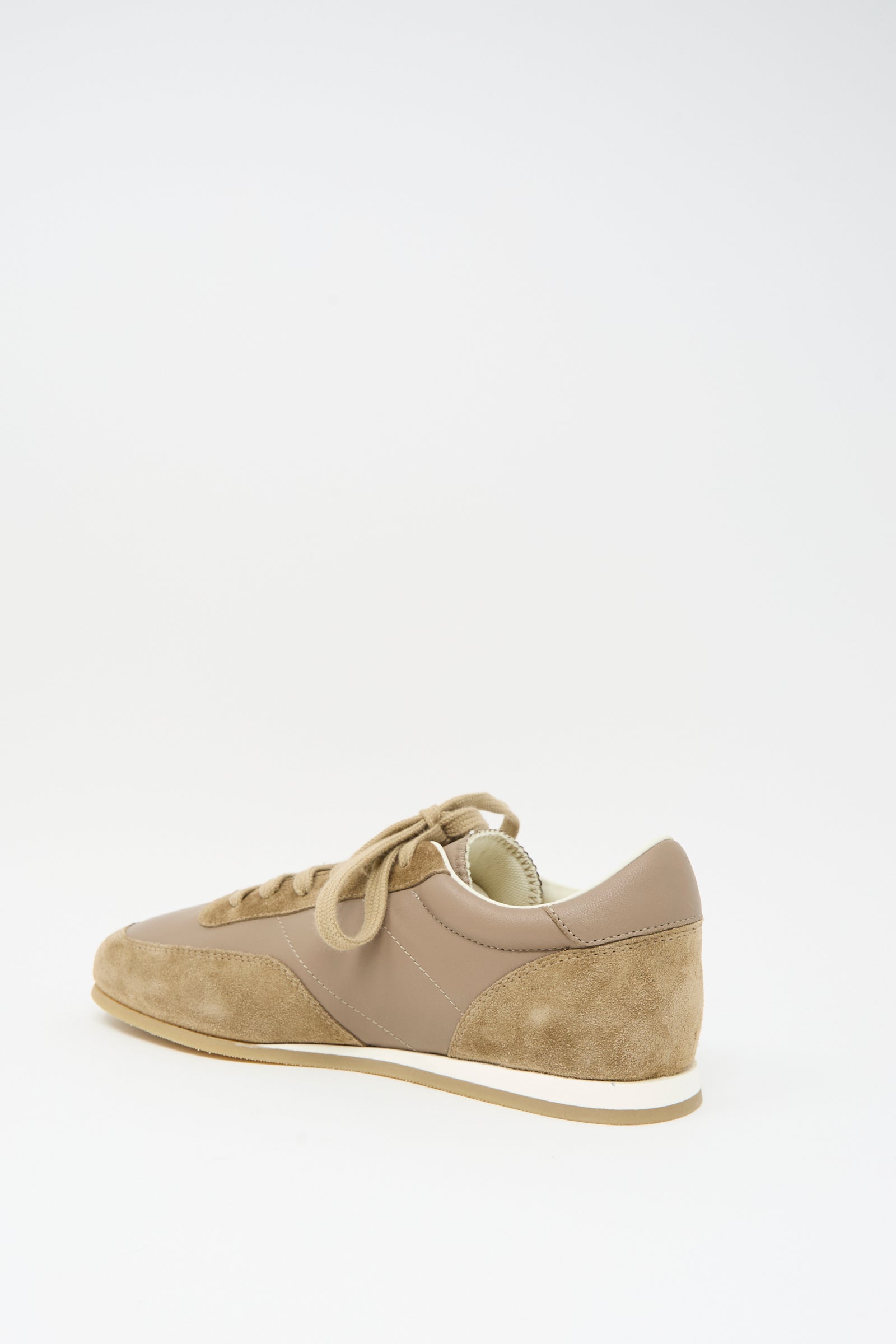 The Common Projects Minimal Runner Article 4182 in Taupe is a low-top sneaker in calfskin suede and leather, featuring white and tan rubber soles with laces, expertly crafted in Italy and shown against a white background.