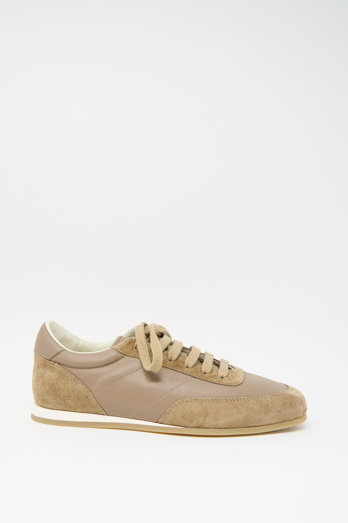 The Minimal Runner Article 4182 in Taupe by Common Projects is a low-top sneaker in beige and tan calfskin suede and leather, featuring beige laces and a white sole, shown on a plain white background.