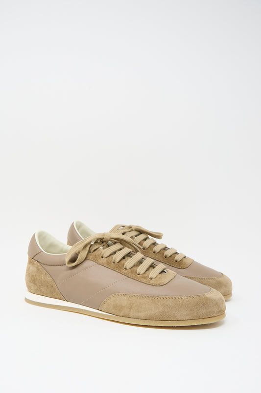 The Common Projects Minimal Runner Article 4182 in Taupe is a pair of low-top sneakers crafted in Italy with tan and beige calfskin suede and leather panels, white midsoles, and tan laces, shown against a white background.
