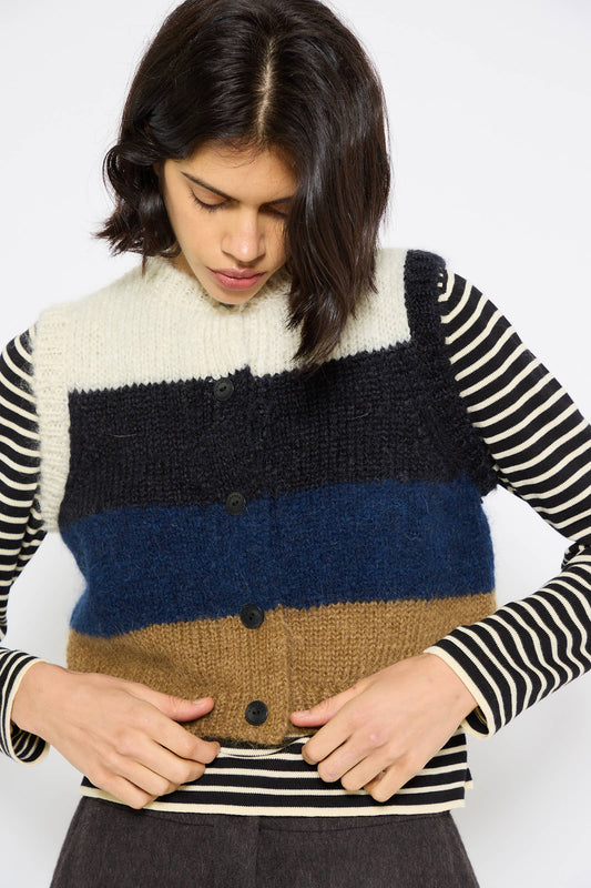 A person with short dark hair looks down while adjusting Cordera's Alpaca and Mohair Waistcoat in Striped over a long-sleeve, black and white striped shirt.