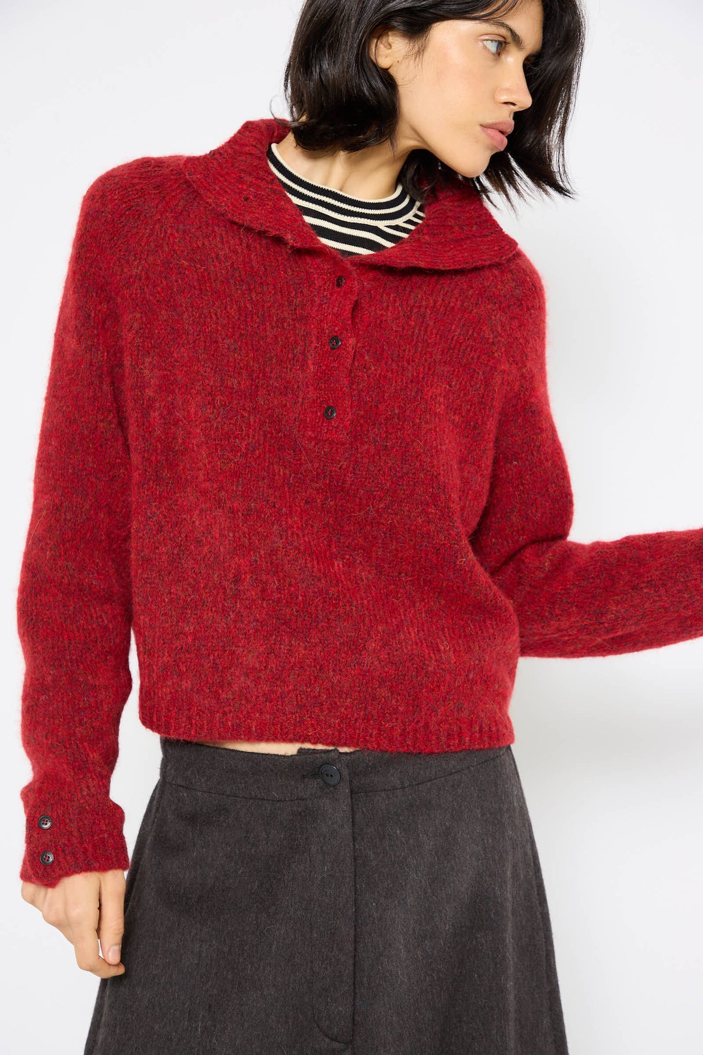 A person wearing a Cordera Baby Alpaca Polo Sweater in Dahlia and a dark skirt, posed against a white background.