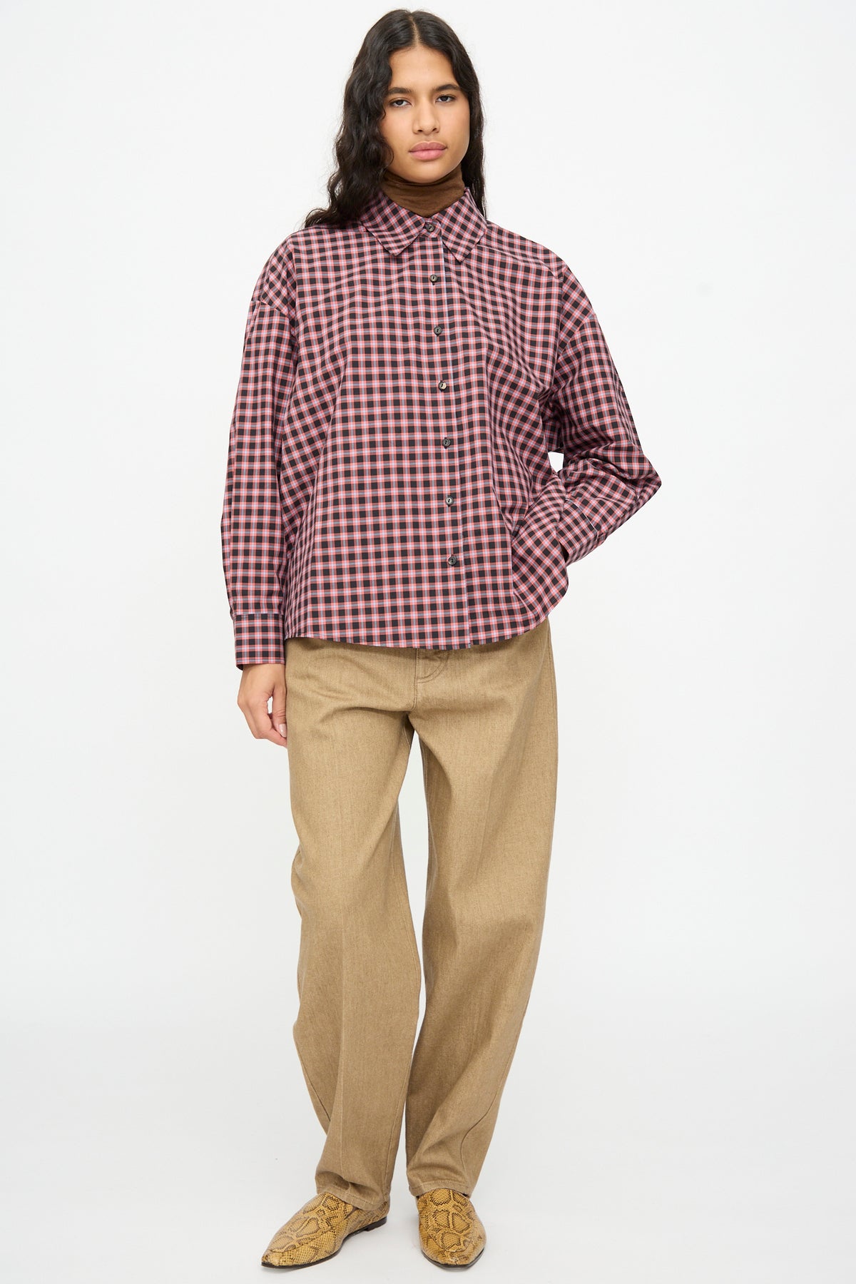 Person wearing a Cordera Checked Oversized Shirt in Orange and Black, paired with tan trousers and snakeskin-patterned boots.