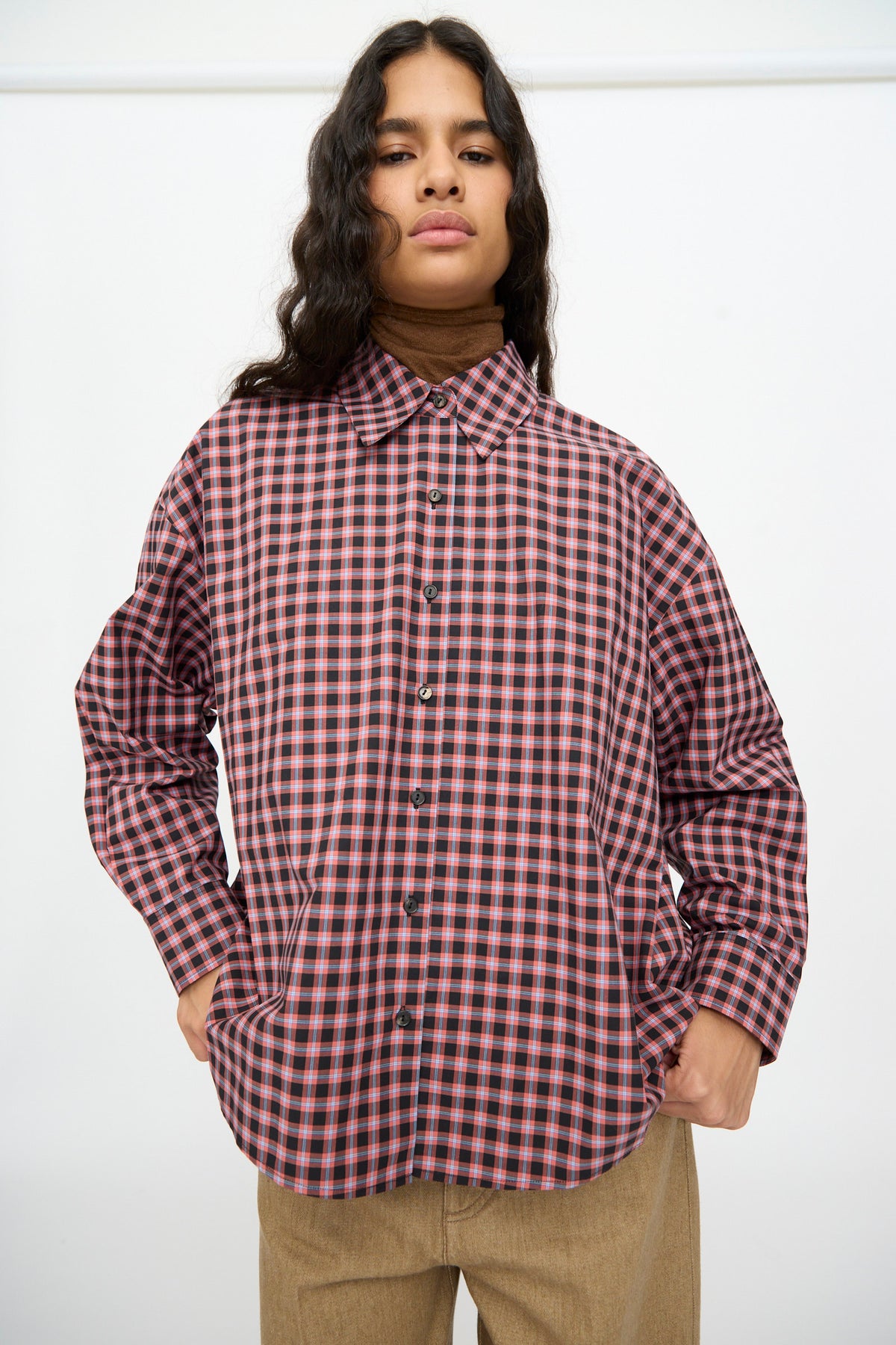 Person wearing a Cordera Checked Oversized Shirt in Orange and Black, featuring an oversized, long-sleeved button-down design with an Italian collar.