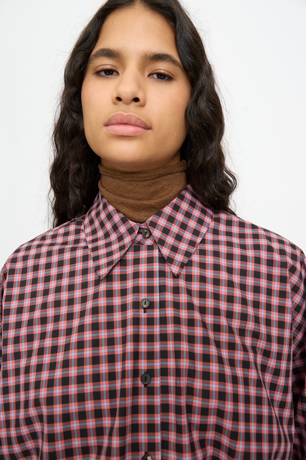 Cordera Checked Oversized Shirt in Orange and Black, featuring a cotton grid pattern layered over a brown turtleneck.