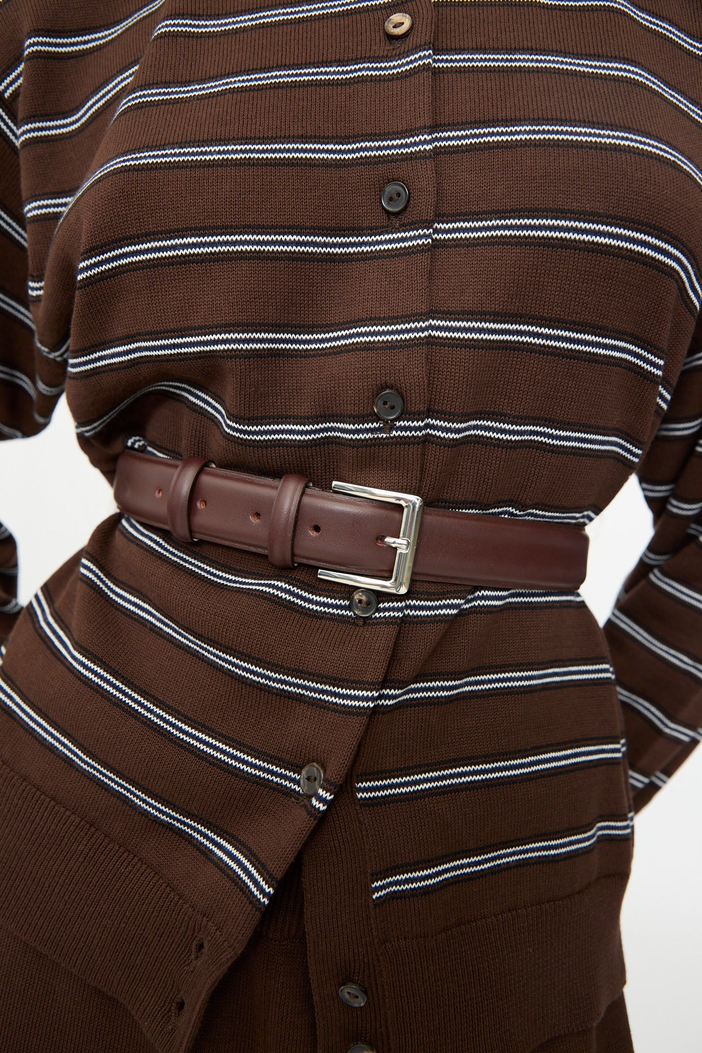 A brown striped shirt dress is cinched at the waist with Cordera’s Classic Belt in Prune, expertly crafted in Spain from calfskin leather and finished with a sleek silver buckle.