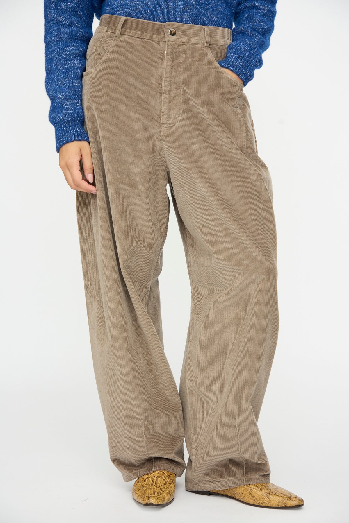 Person wearing sage green Cordera Corduroy Baggy Pants in Sage with an elastic waistband and snakeskin-print loafers.