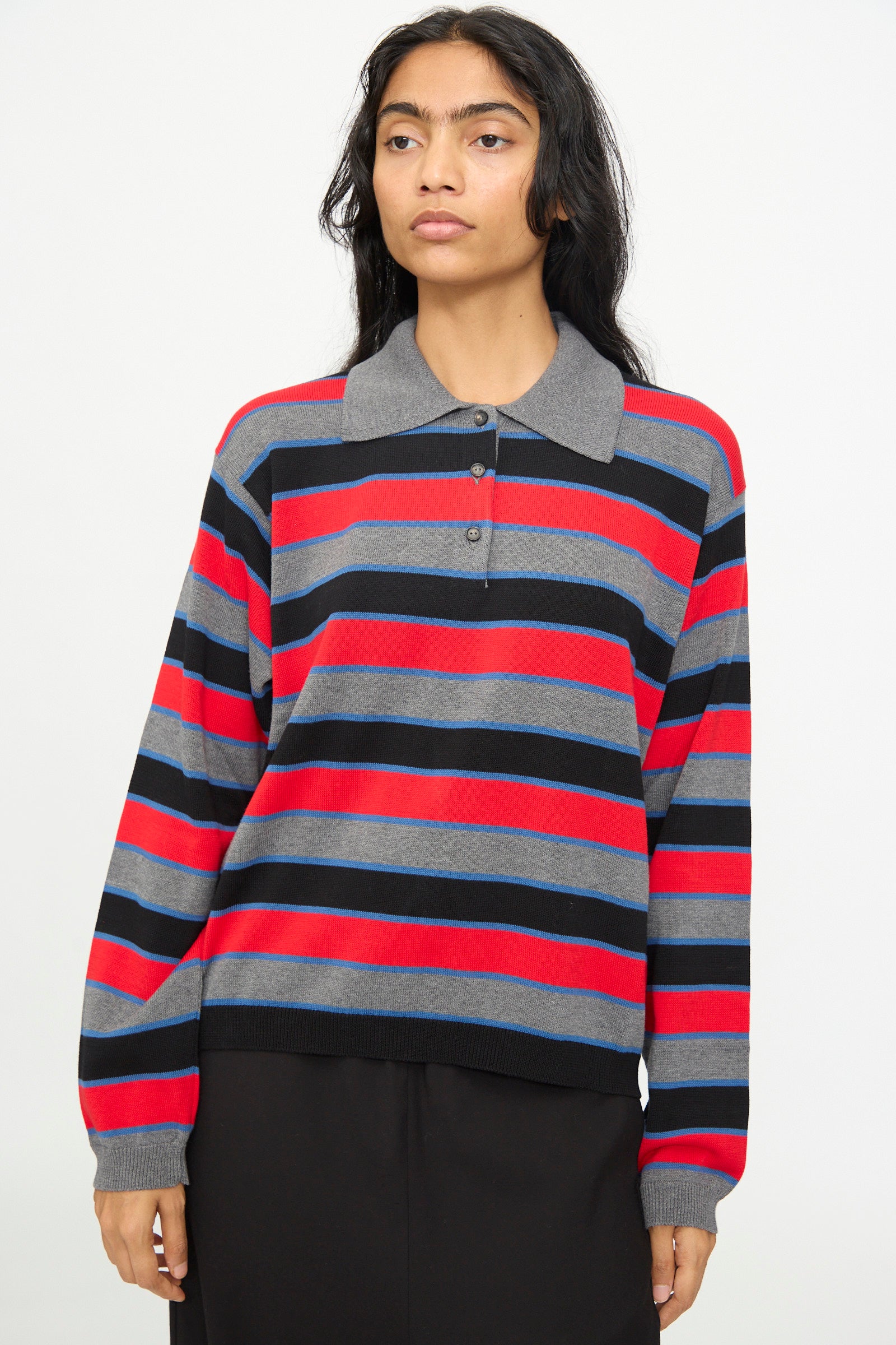 A person wearing the Cordera Cotton Long Sleeve Polo in Stripe, featuring an oversized fit with gray, red, black, and blue stripes and a collar, stands against a plain background.
