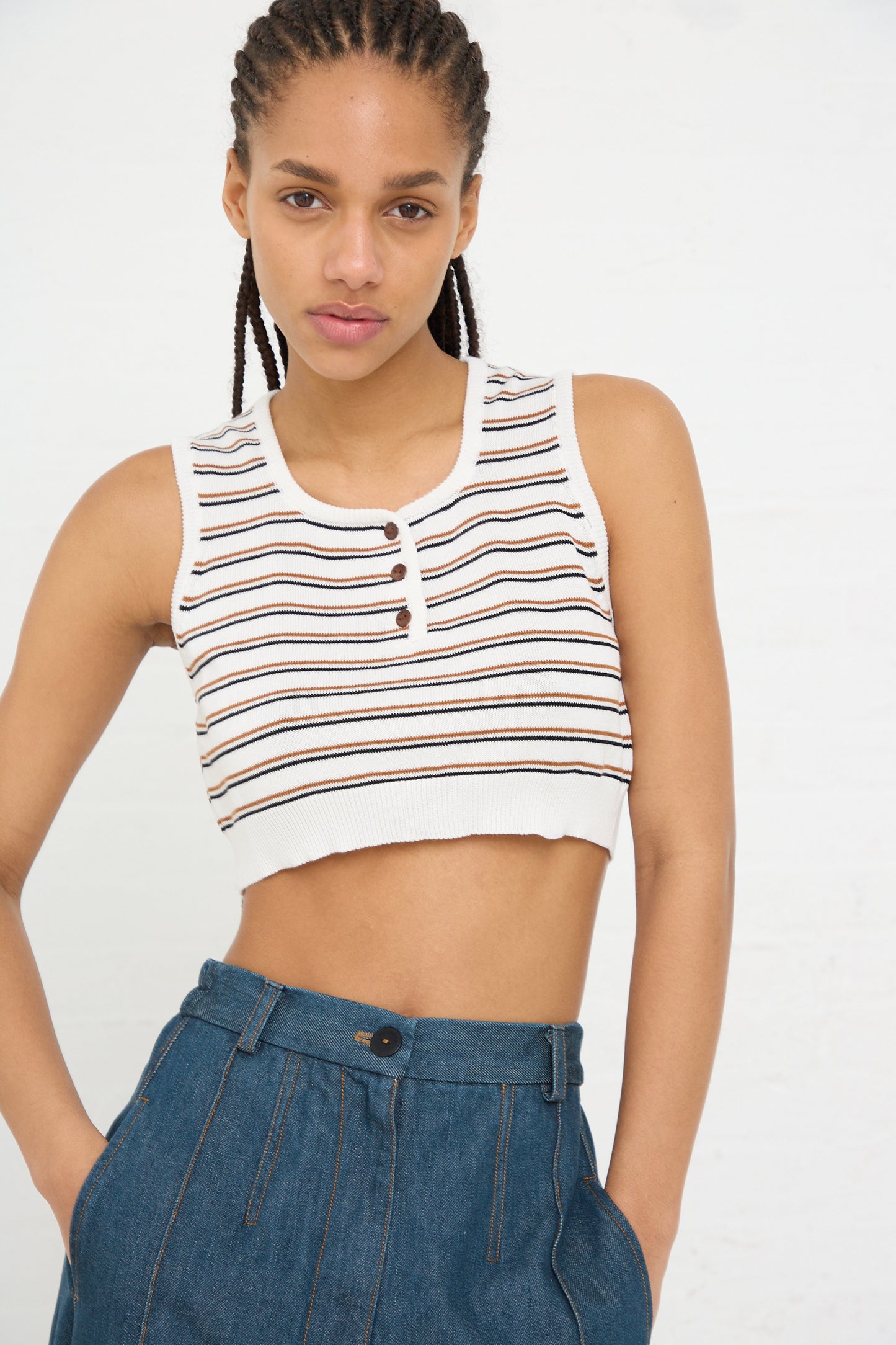 A woman in a Cordera organic cotton striped crop top and high-waisted denim pants posing for the camera.