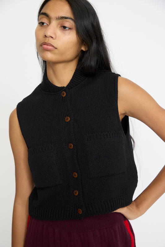 A person with long dark hair wears Cordera's Cotton Waistcoat in Black, featuring a sleeveless design and bomber collar, looking to the side with a neutral expression.