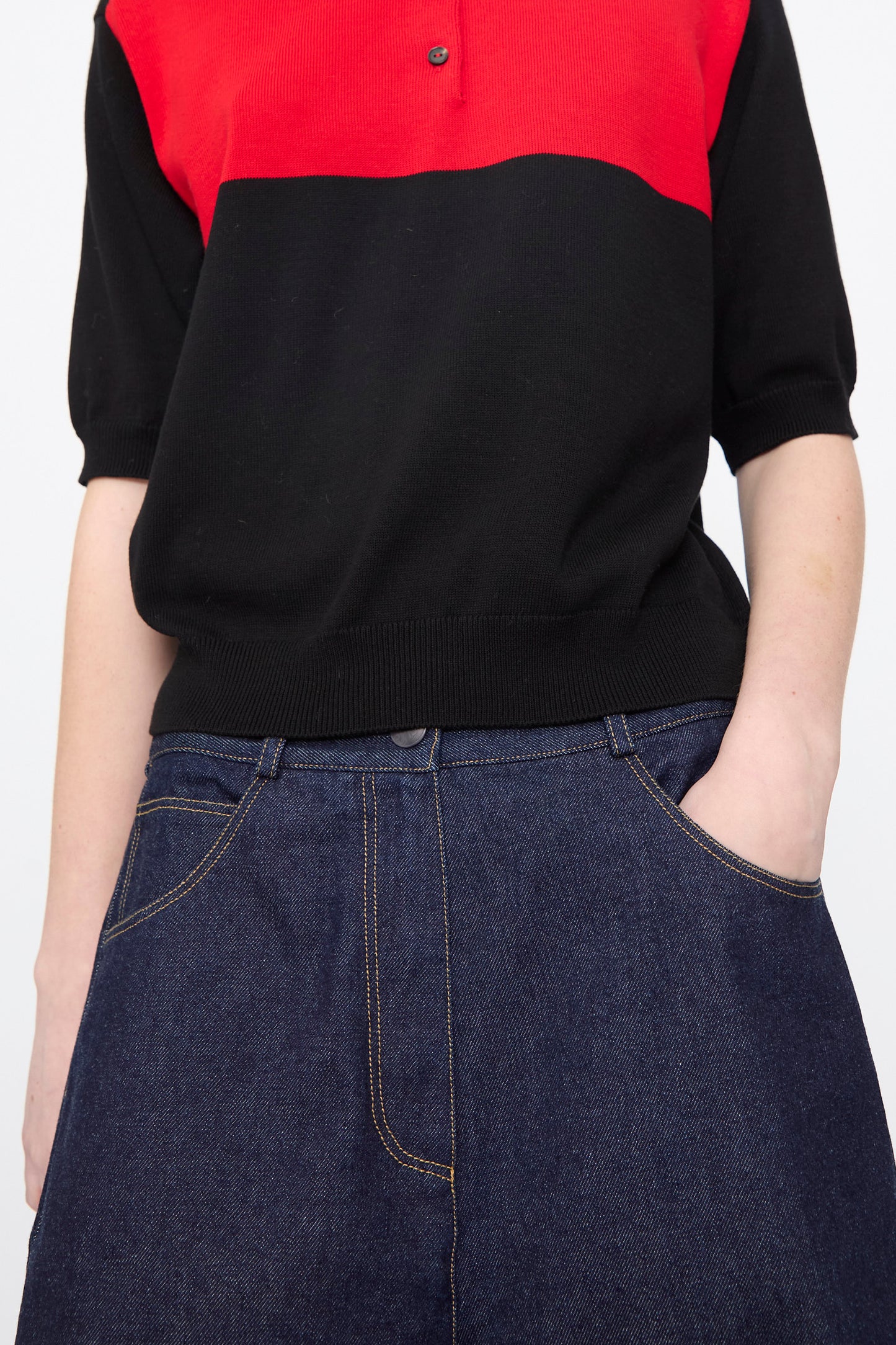 Person wearing Cordera Curved Baggy Jeans in Denim—relaxed fit blue jeans made from organic cotton denim—with one hand in their pocket, photographed from shoulders to hips.
