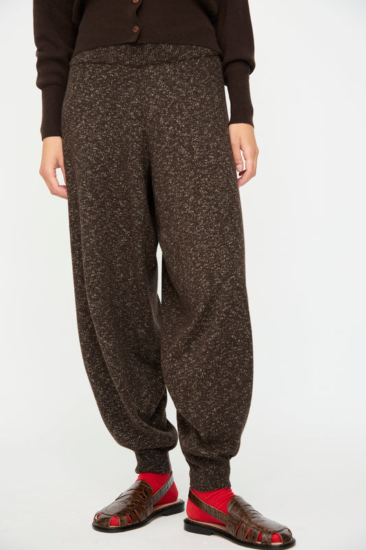 Model wears Cordera's Flecked Cotton Pant in Brown with a matching sweater, red socks, and brown open-toe sandals, standing against a plain white background. Made in Spain.