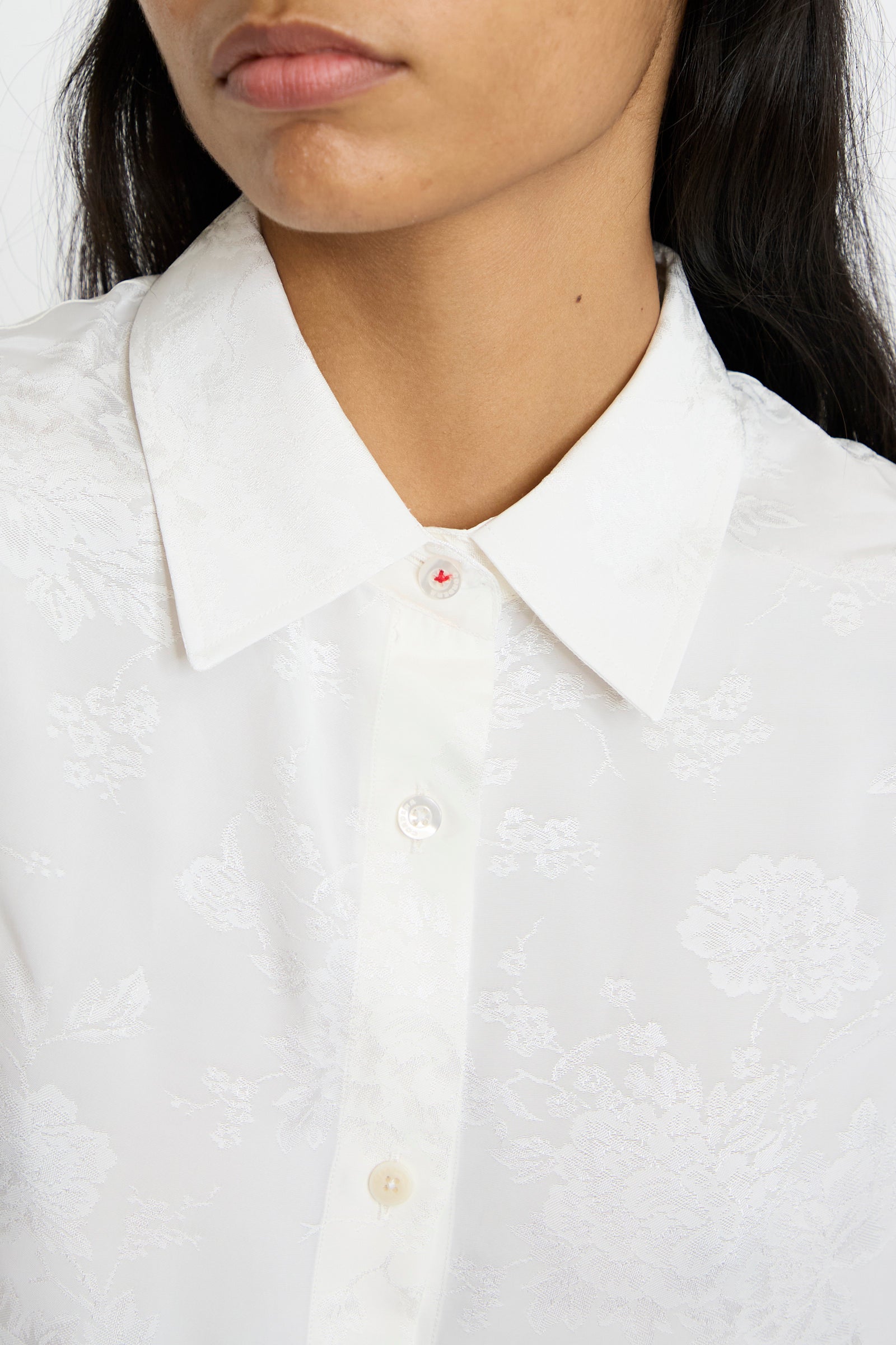 Close-up of a person wearing the Cordera Flower Jacquard Shirt in White, featuring a red-threaded buttonhole detail.