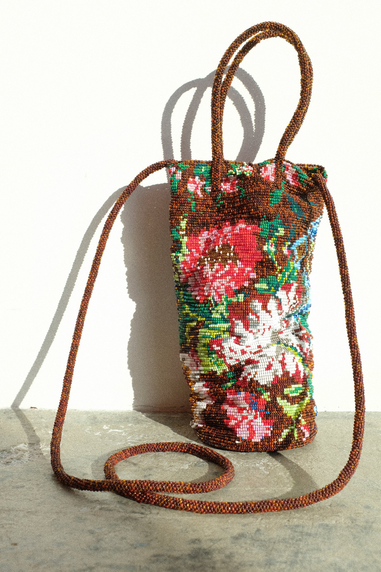 Cordera's Handmade Beaded Bag in Peonia on the floor against a white wall.