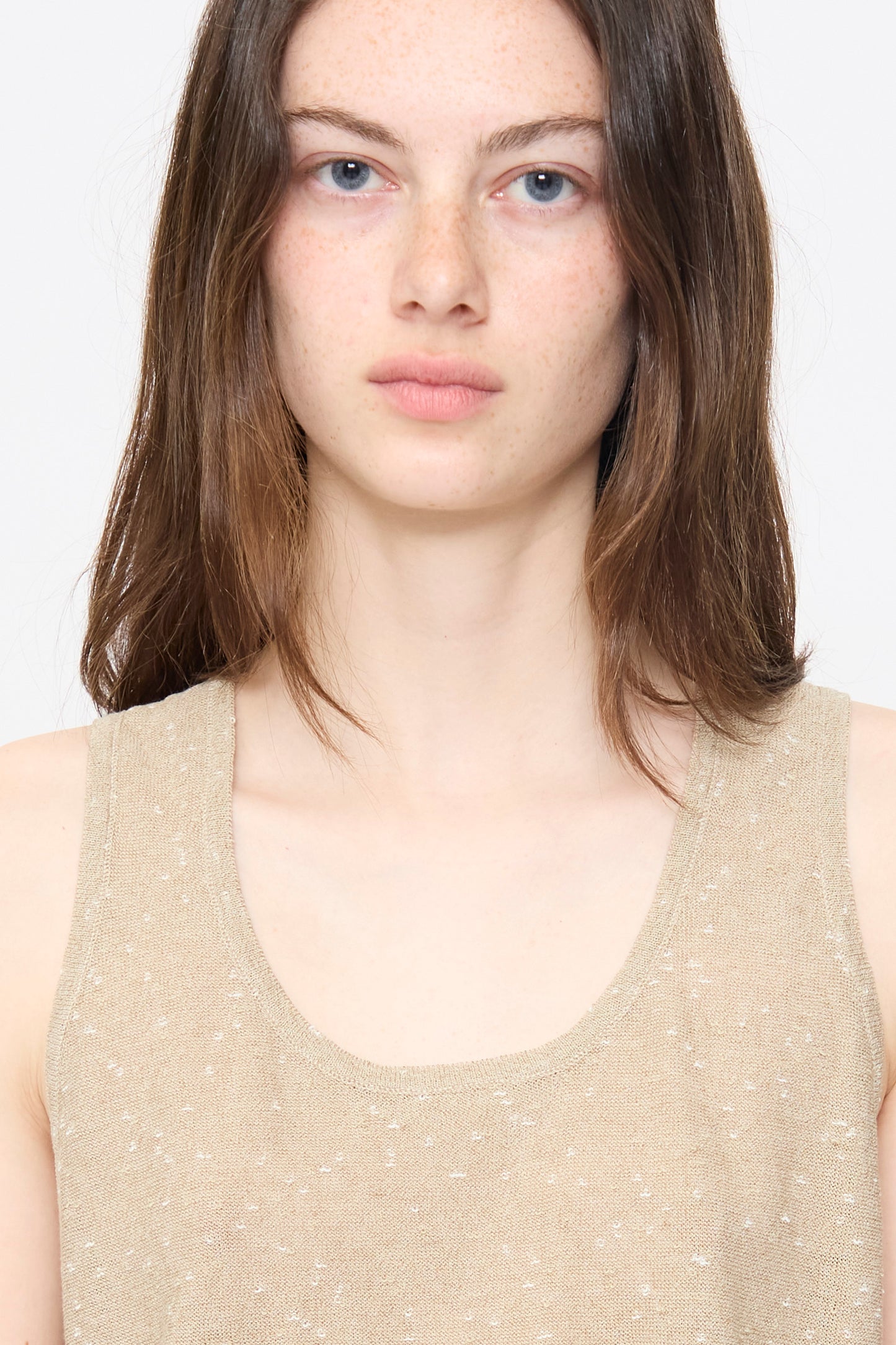 A person with fair skin, blue eyes, and brown hair wears the Cordera Linen and Cotton Flecked Tank Top in Beige, looking straight at the camera against a plain white background.