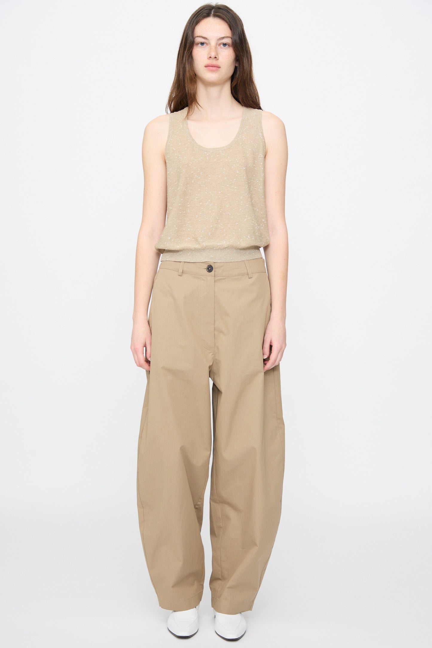 A person wearing the Cordera Linen and Cotton Flecked Tank Top in Beige stands facing forward against a plain white background, paired with loose-fitting beige pants.