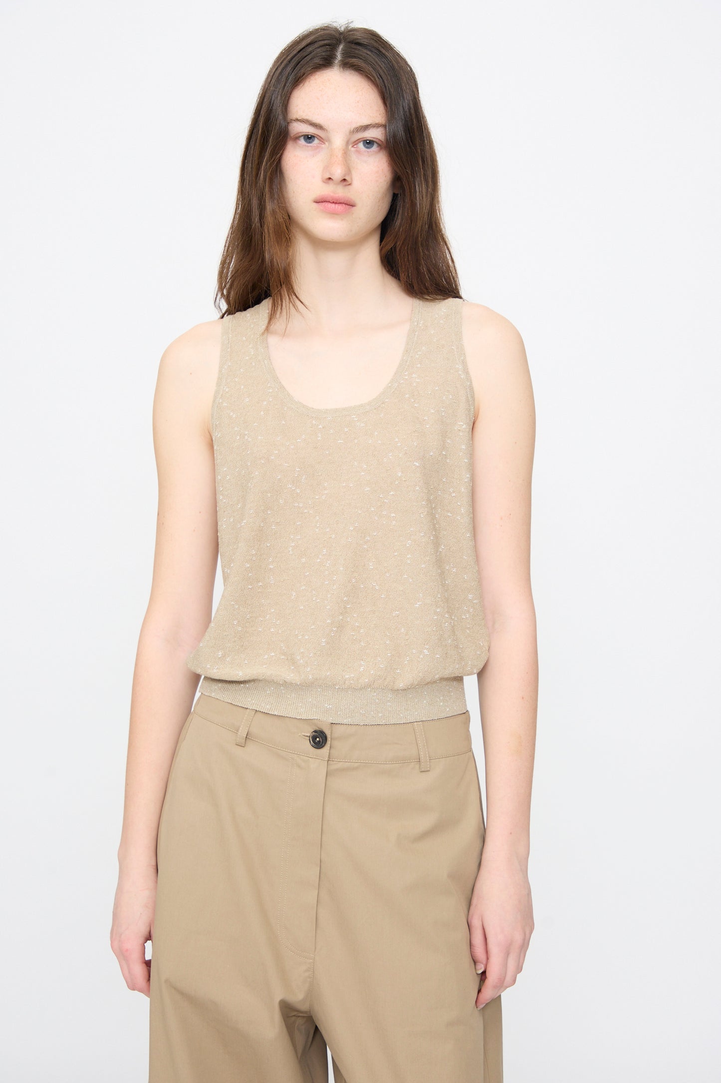 A person models the Cordera Linen and Cotton Flecked Tank Top in Beige, paired with tan high-waisted pants, standing against a plain light gray background.