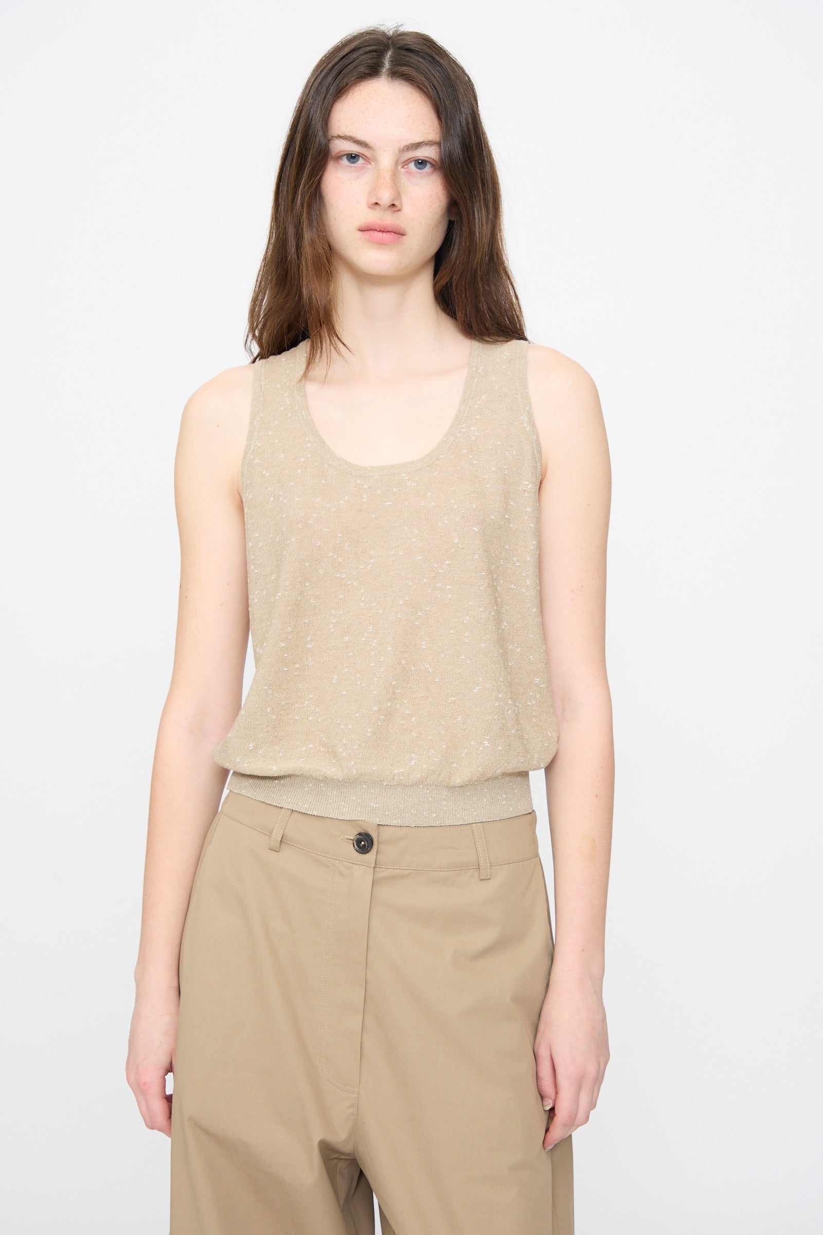A person models the Cordera Linen and Cotton Flecked Tank Top in Beige, paired with tan high-waisted pants, standing against a plain light gray background.