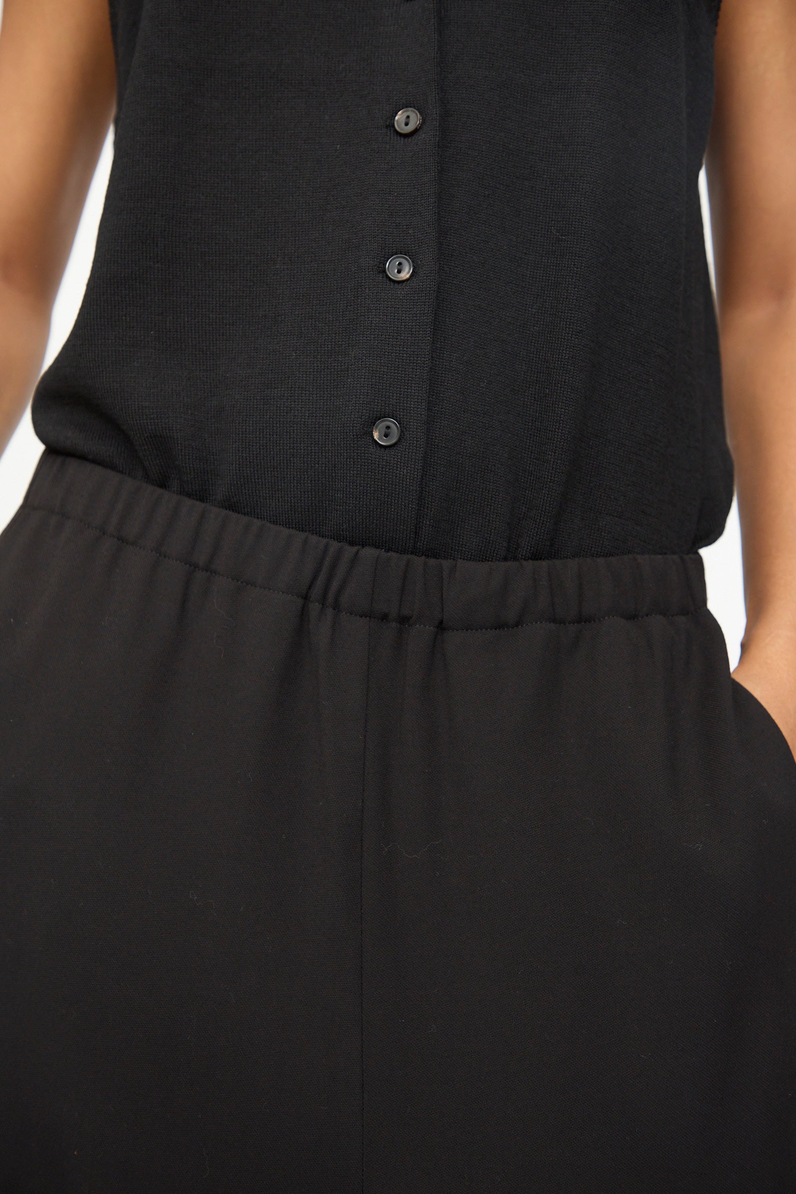 A person wearing Cordera’s black Lounge Pants, featuring an elastic waistband and casual pockets, paired with a sleeveless black button-up top.